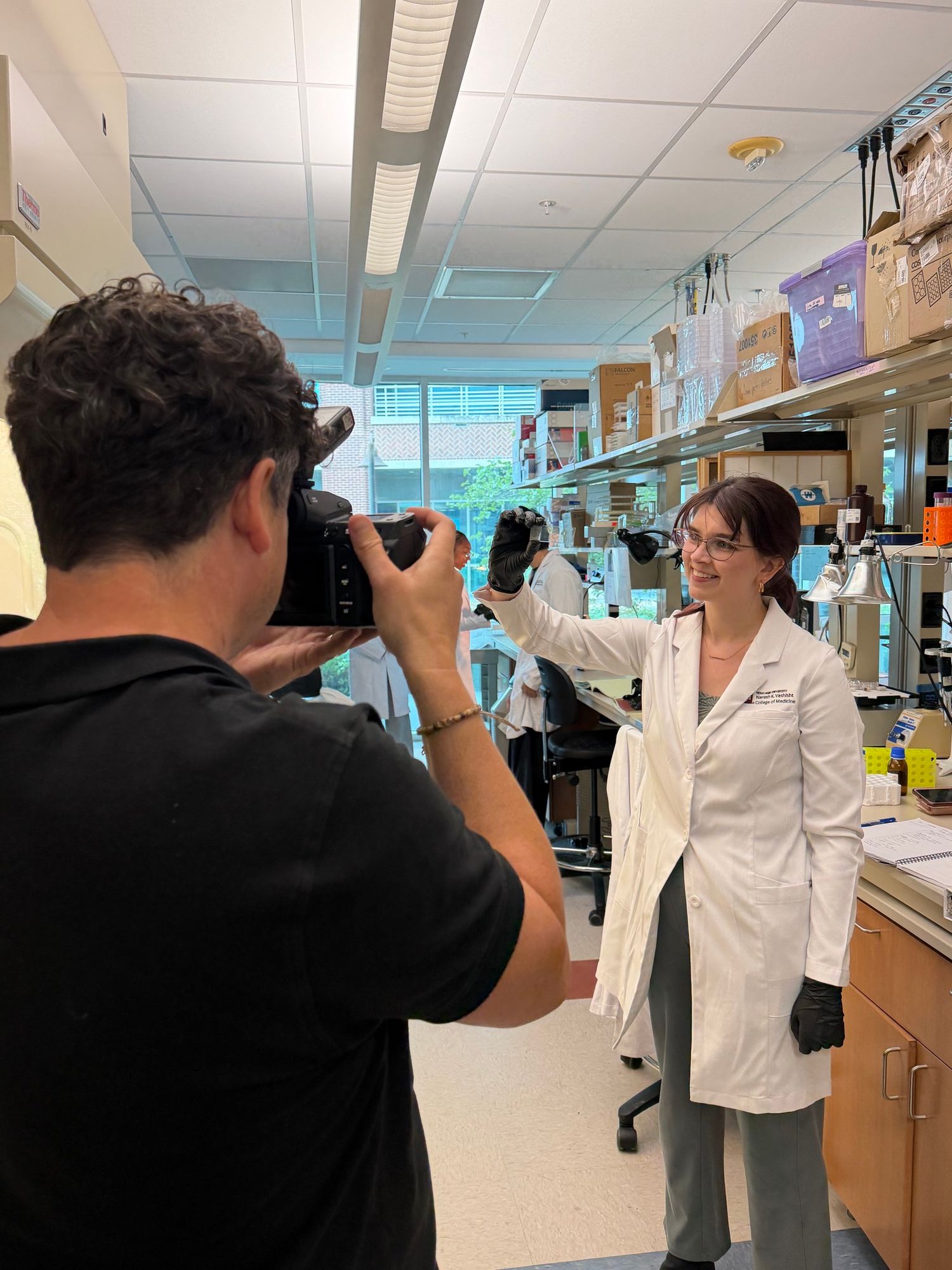 Photographer captures portrait of female scientist in white lab coat in a research laboratory.