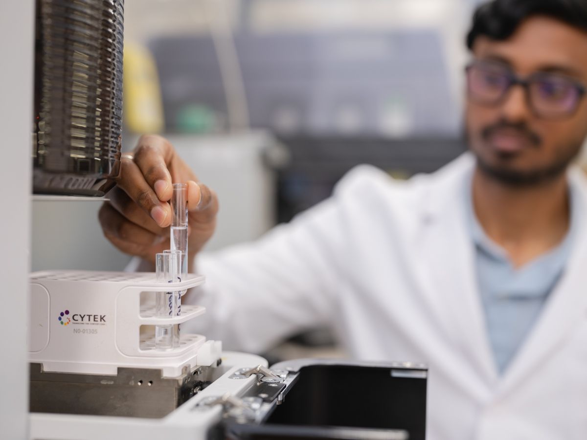A scientist in a white lab coat uses a Cytek instrument in a modern research laboratory.