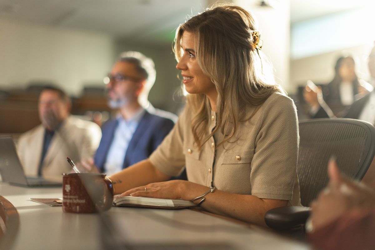 Focused blonde businesswoman listening attentively during corporate meeting in conference room.