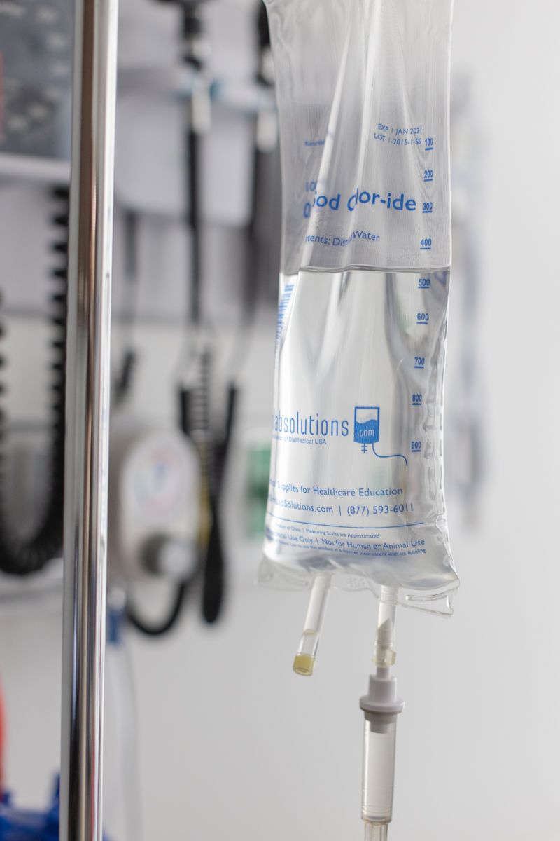 An IV saline sodium chloride drip bag hanging on a medical pole in a clinical setting.