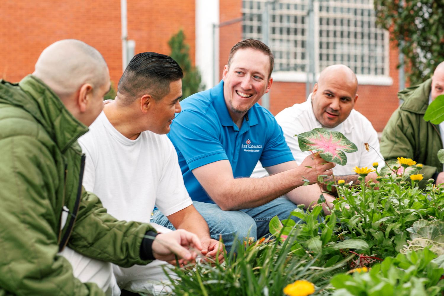 Group of people smiling and examining plants together in a garden.
