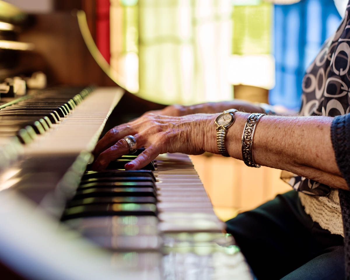 Elderly hands with jewelry playing piano keys, close-up shot of senior musician performing.