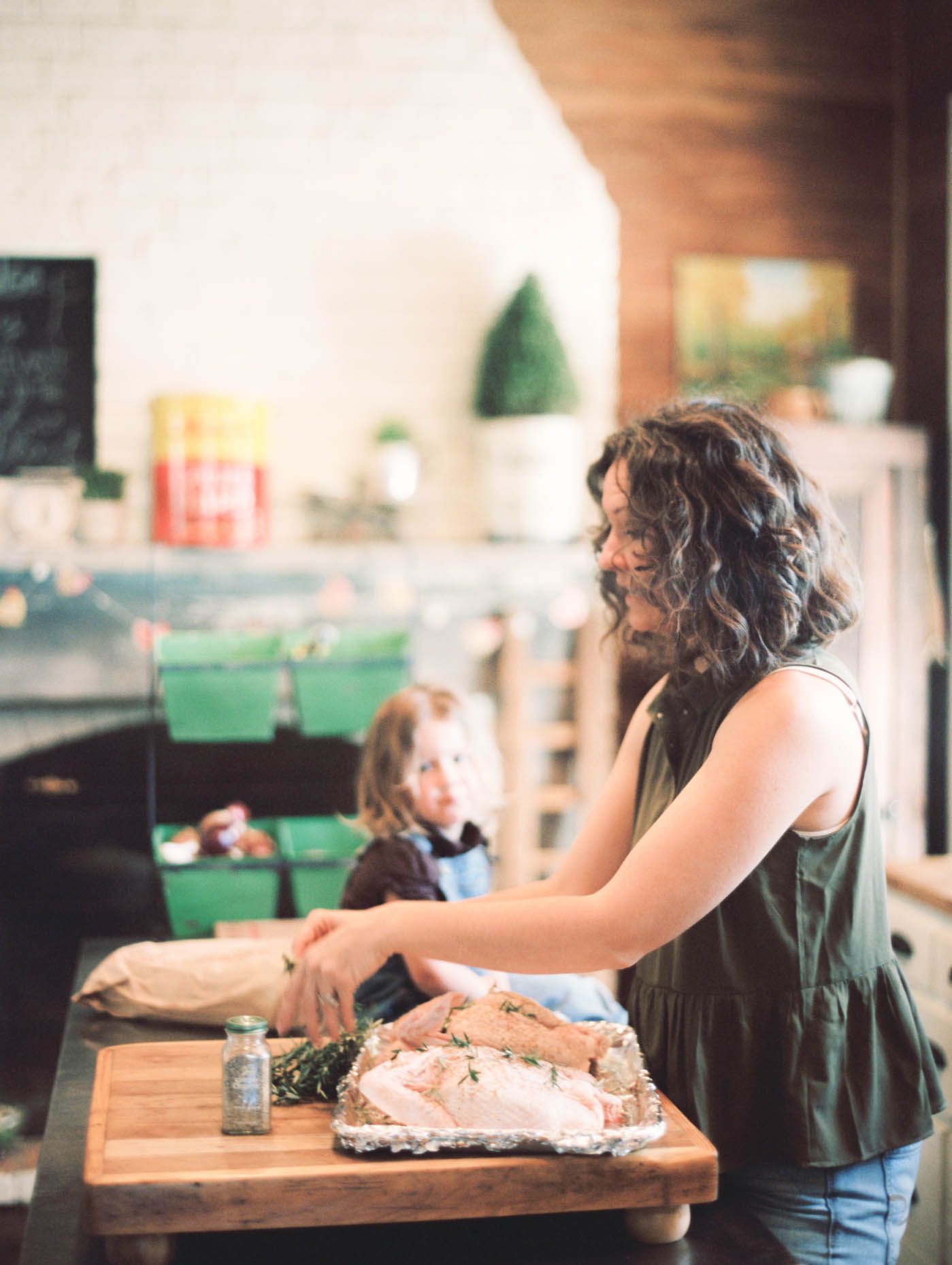 Woman preparing a roast on a wooden cutting board in a cozy farmhouse kitchen.