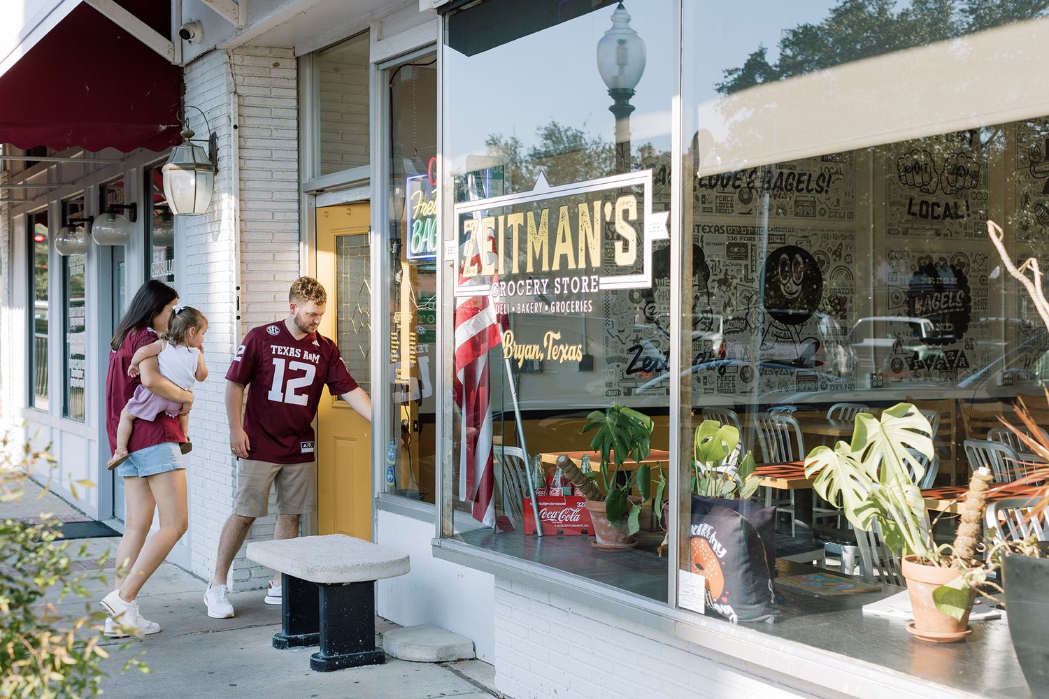 Couple walking past Pitman's store front on a sunny day in a charming small town shopping district.
