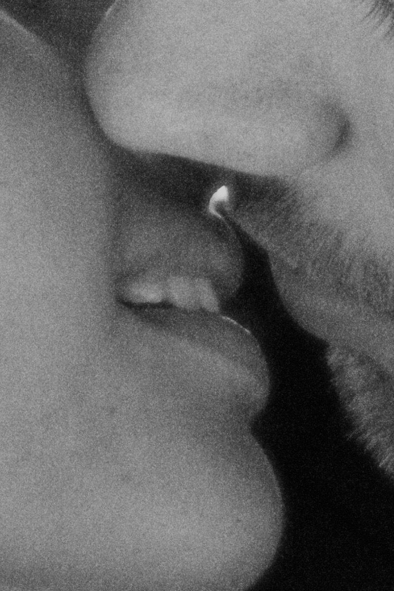 Close-up black and white photo of a couple sharing a passionate kiss.