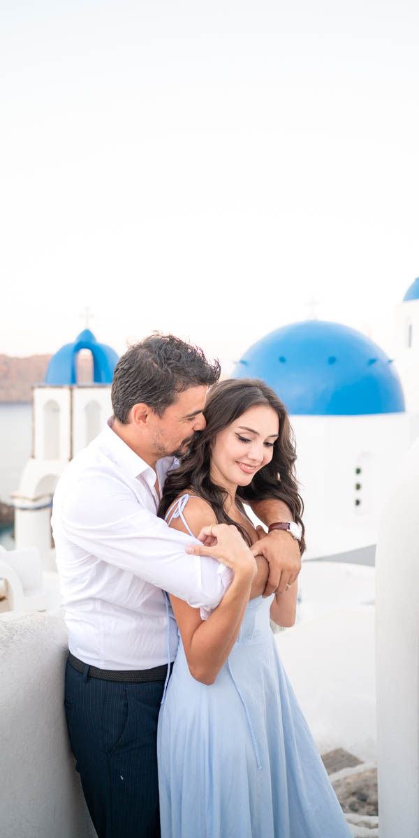 A couple posing during a photo shoot in Oia village in Santorini next to the blue dome churches