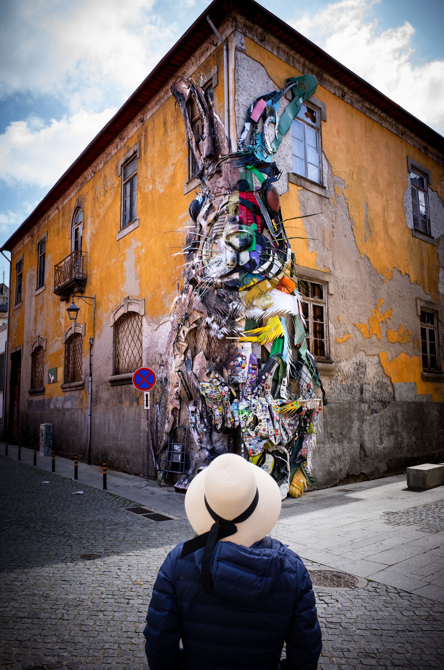 Woman in a sun hat views Bordalo II's Half Rabbit sculpture in Porto, Portugal, from the FotoMunki Hat Series.