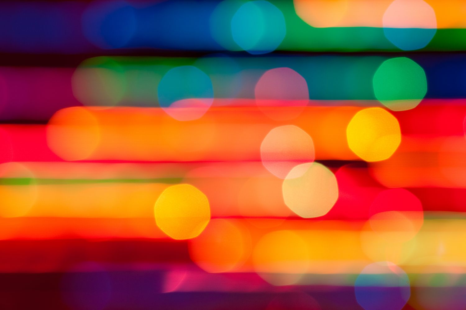 Abstract fine art of colorful blurry Christmas lights with vibrant bokeh circles and glowing holiday light trails.