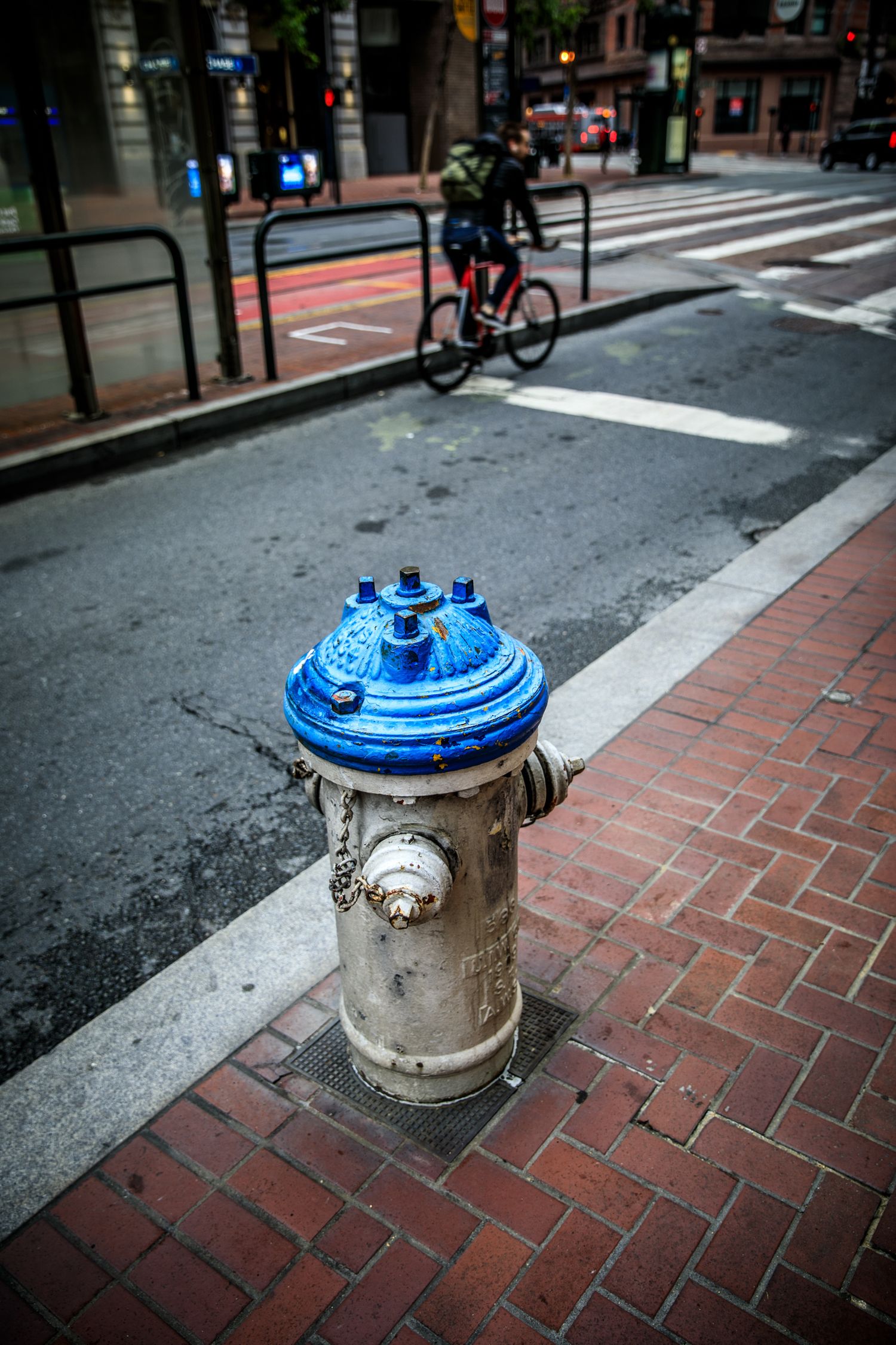 Blue fire hydrant and passing cyclist on a downtown San Francisco street, capturing urban motion and everyday city life.