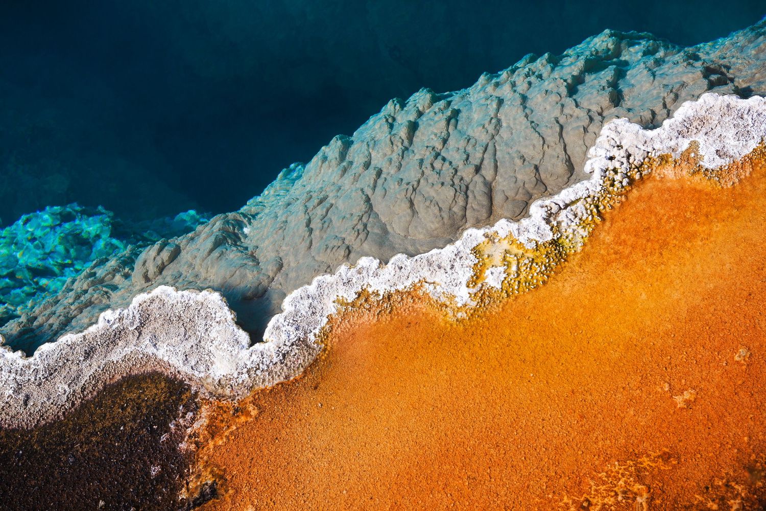 Abstract Yellowstone geothermal landscape with complementary orange and blue hues, vibrant mineral deposits, and turquoise water.