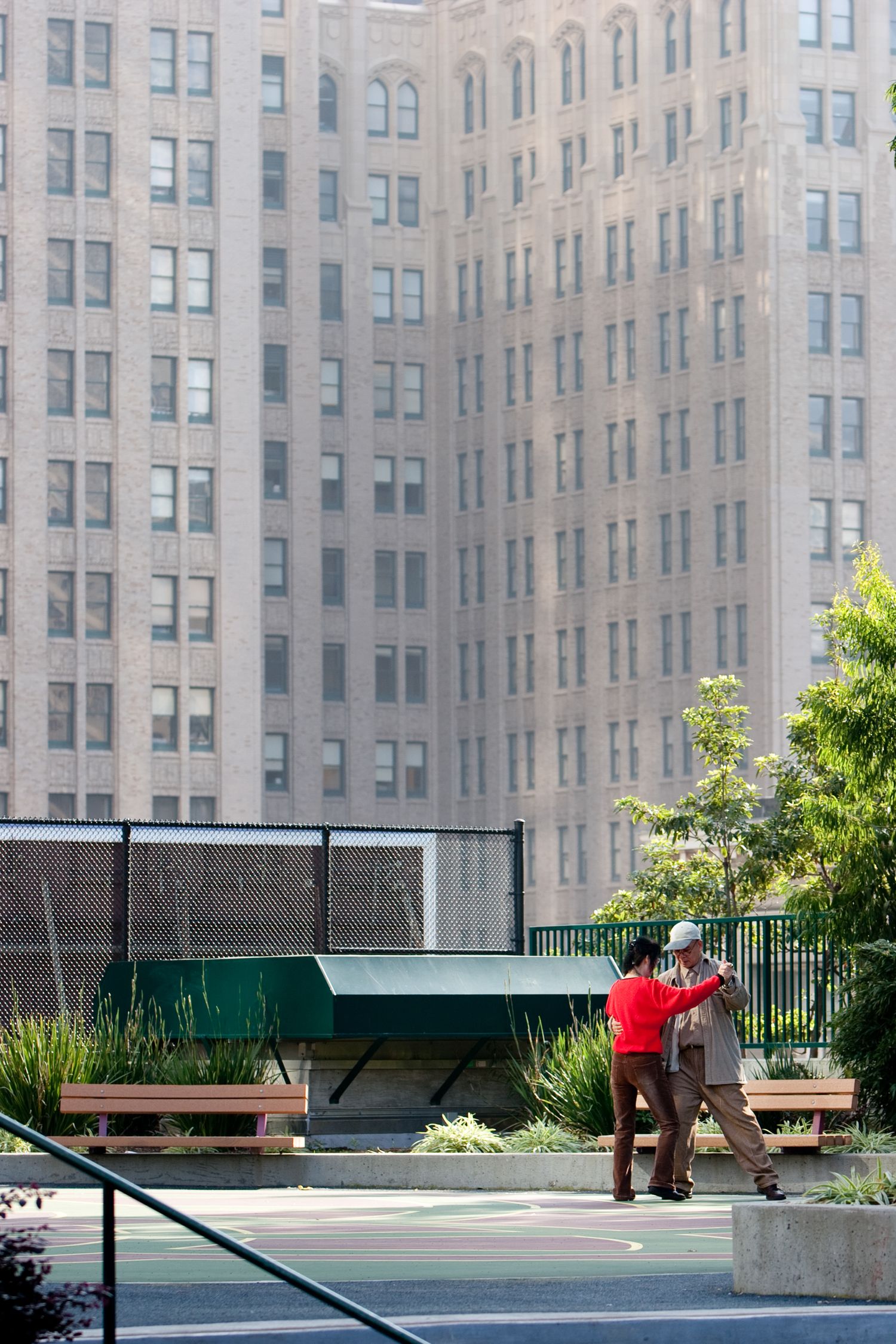 Couple dancing in a San Francisco park beneath towering downtown buildings, capturing an intimate urban street photography moment.
