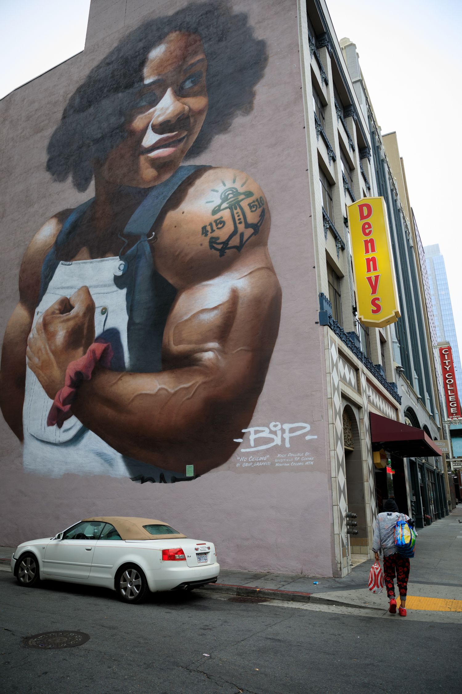 Downtown San Francisco street scene featuring the No Ceiling mural, colorful urban art, and pedestrians beneath towering city buildings.