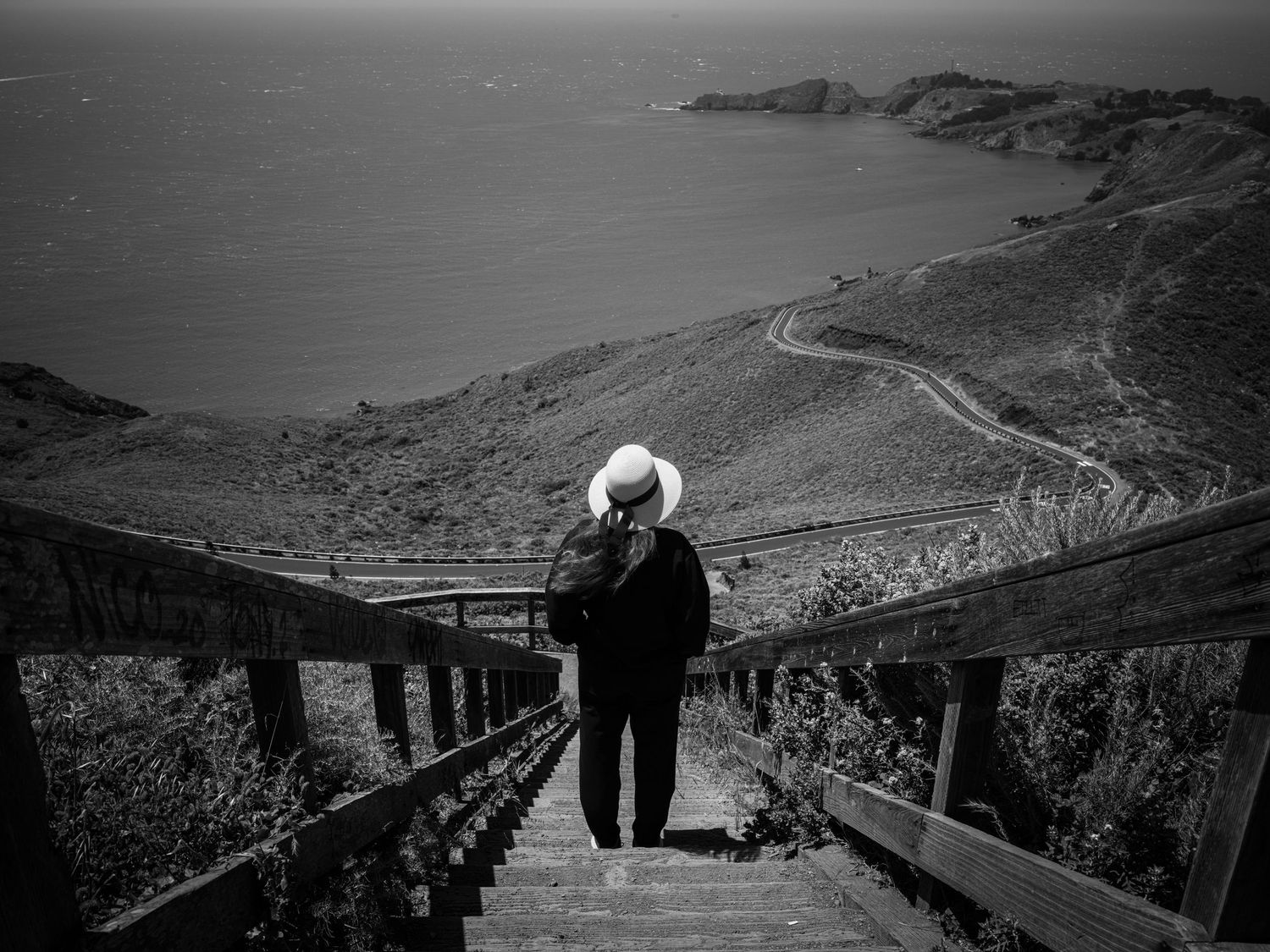 Woman in white hat overlooking the Marin Headlands coastline near San Francisco in a dramatic black and white landscape with leading lines.