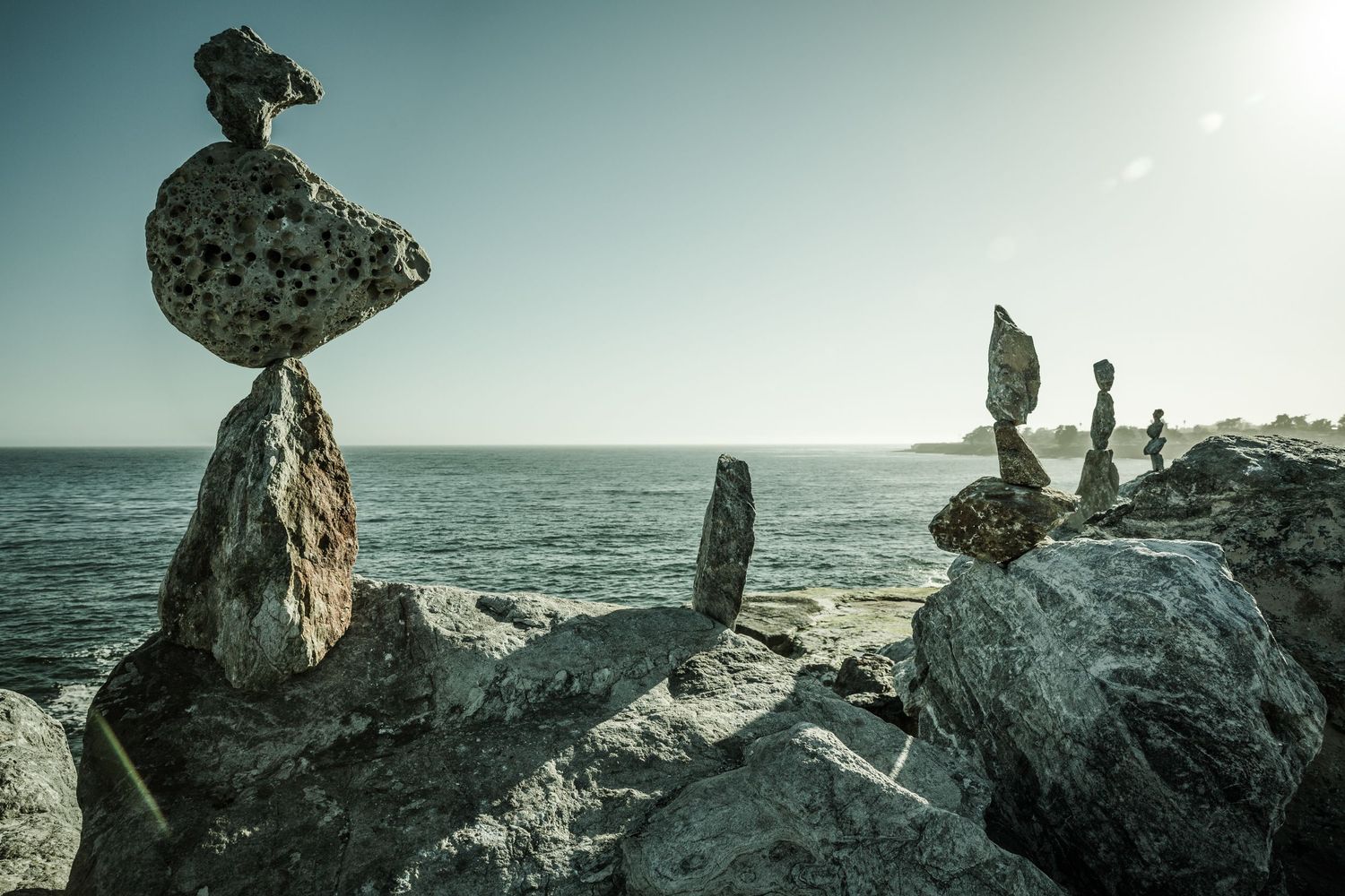 Balanced rock cairns overlooking the Pacific Ocean at sunset in Santa Cruz, California, creating a peaceful fine art landscape.