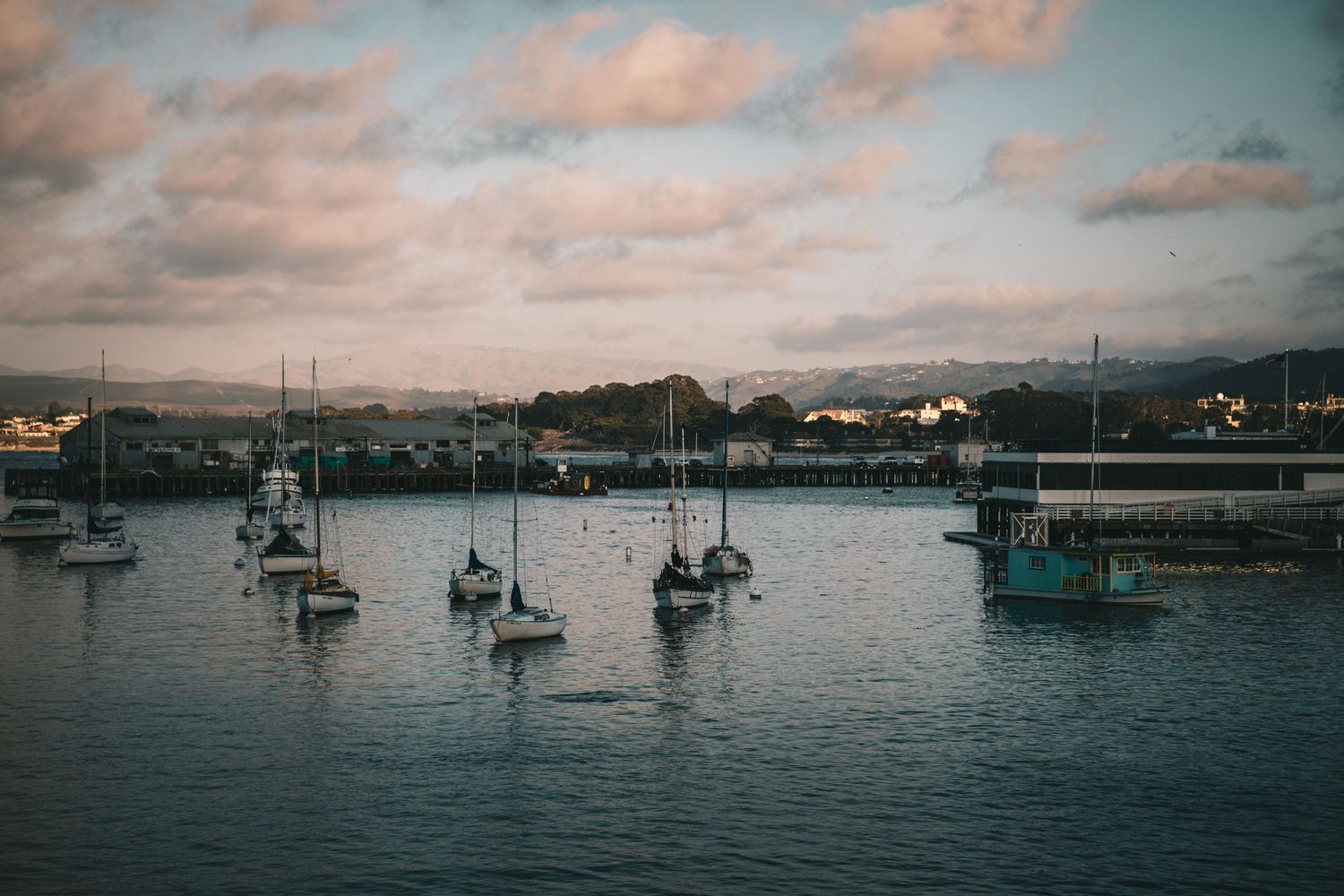 Sailboats at anchor in Monterey Harbor, California beneath pastel evening clouds, capturing the peaceful beauty of the Central Coast.