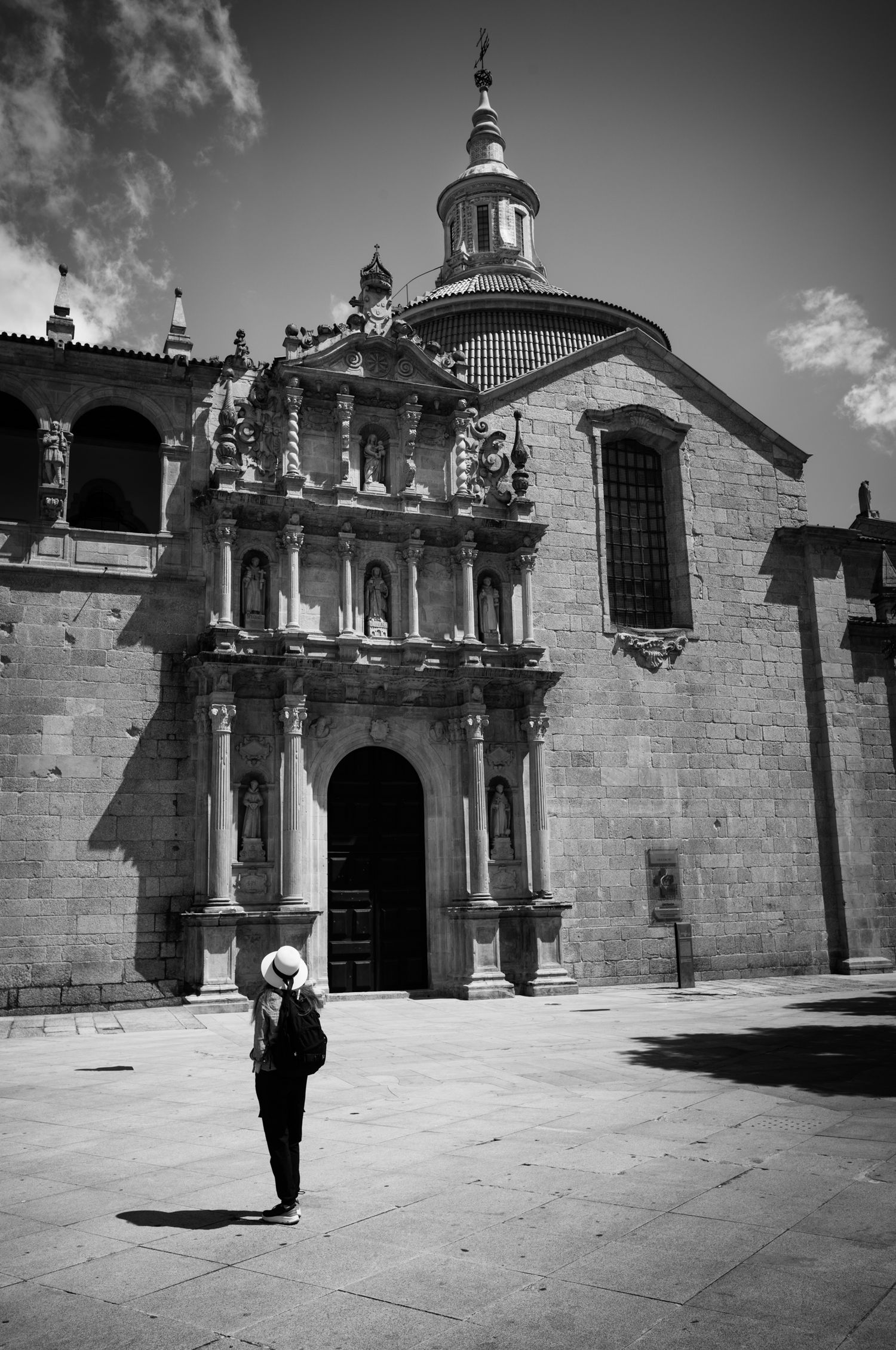 Woman in a white hat stands before Igreja de São Gonçalo in Amarante, Portugal, in a dramatic black and white travel photograph.