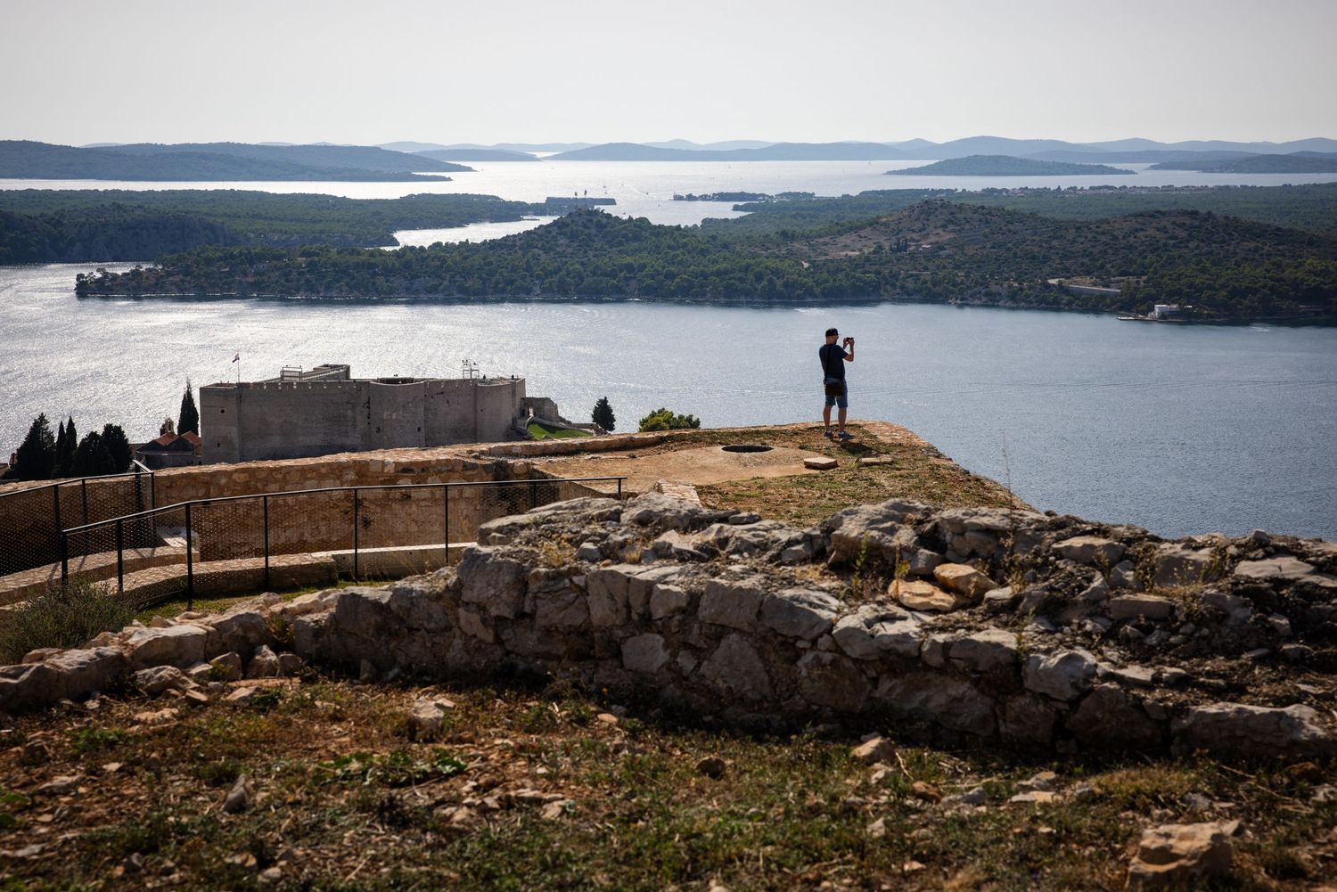 Photographer overlooking the Adriatic Sea from St. John's Fort in Šibenik, Croatia, with Dalmatian islands on the horizon.