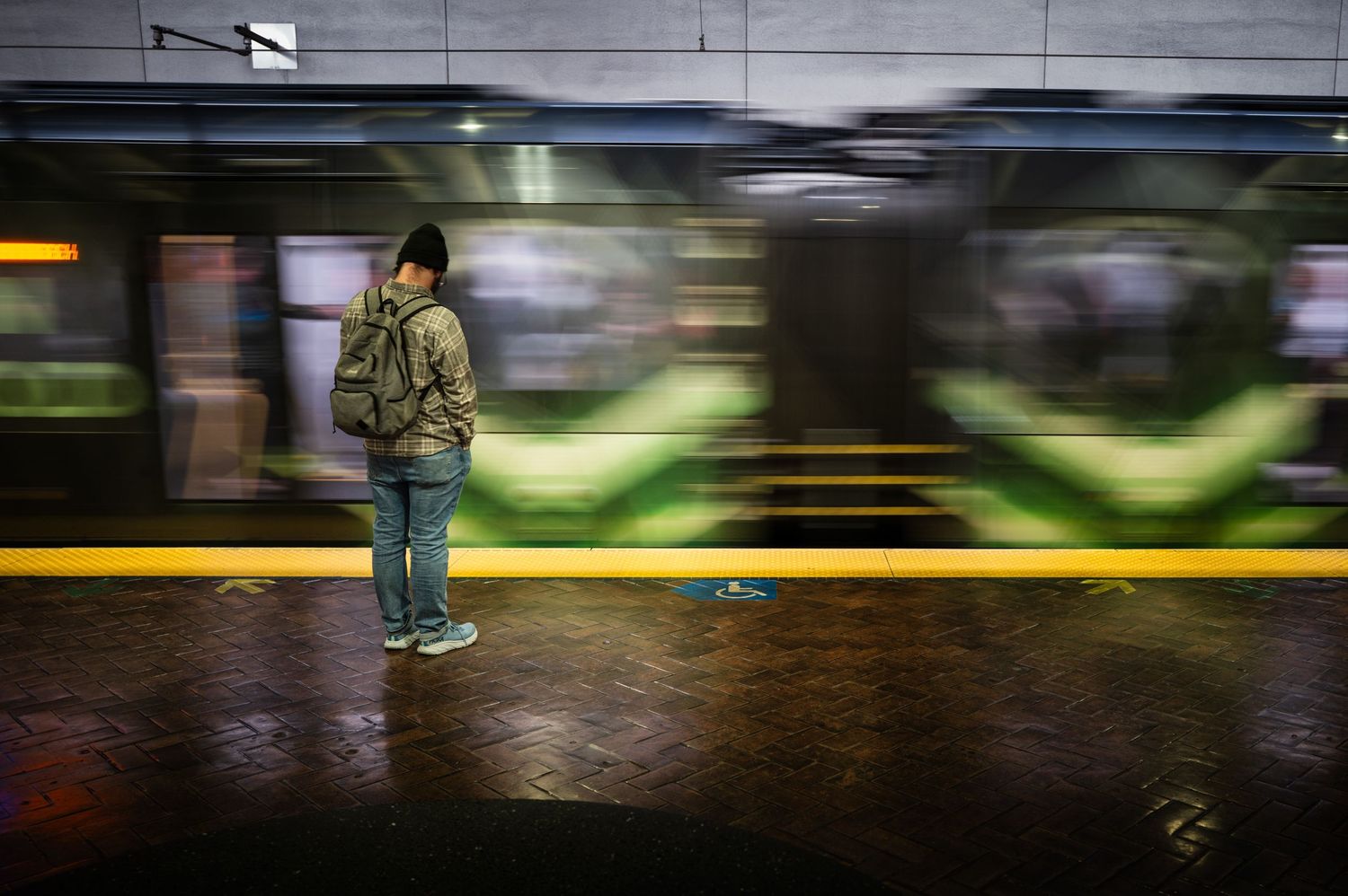 Lone commuter waits as a blurred BART train rushes through a San Francisco station, capturing motion and urban solitude.