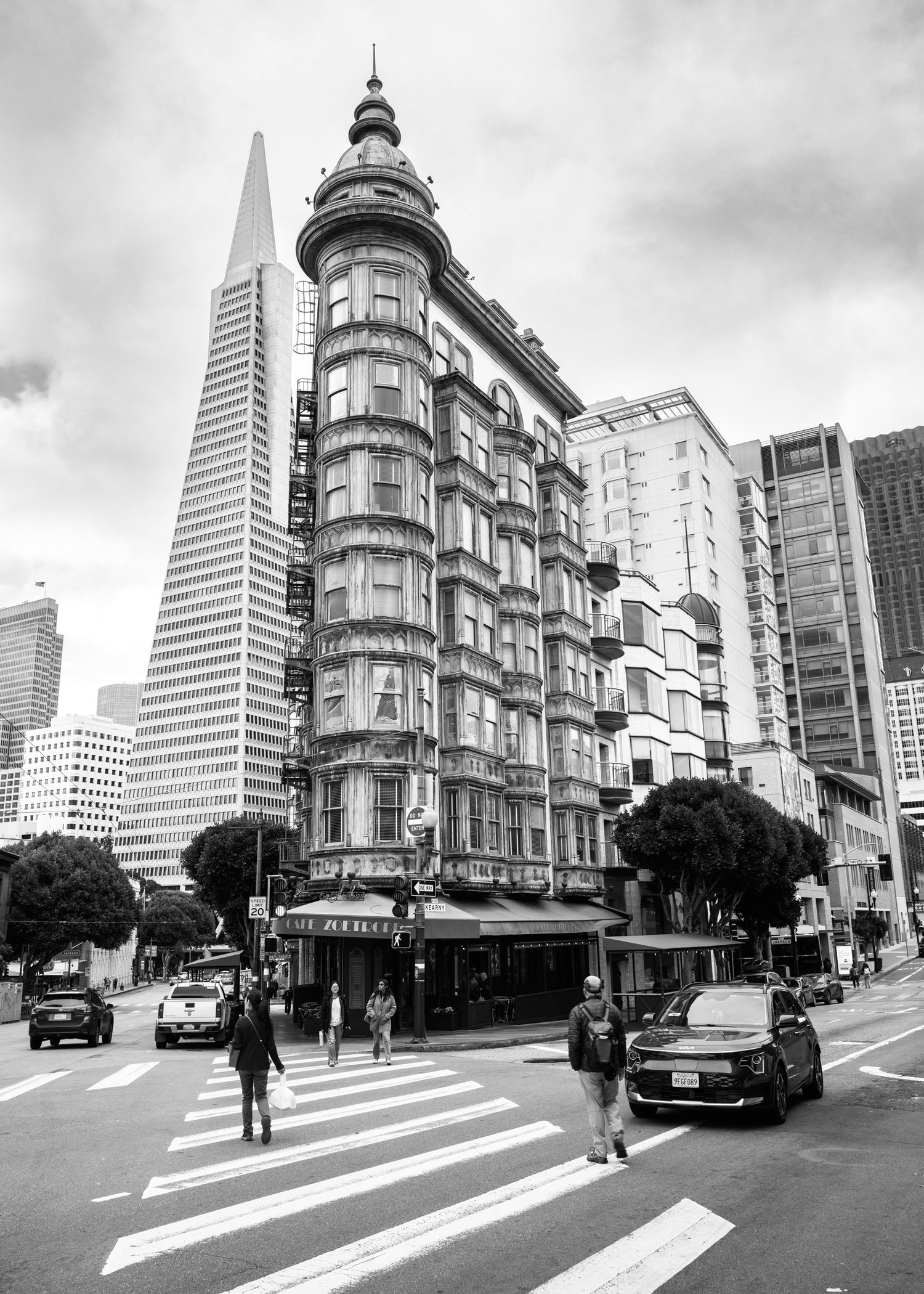 Black-and-white view of San Francisco's Sentinel Building with the Transamerica Pyramid above a downtown crosswalk.