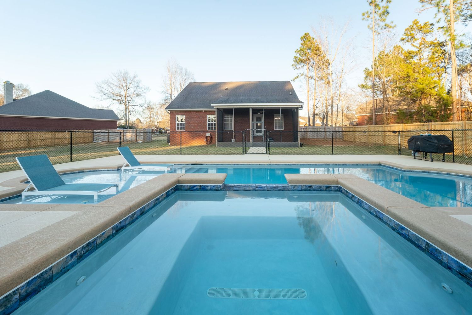 Fenced in swimming pool in Dothan with spa and tanning ledge.