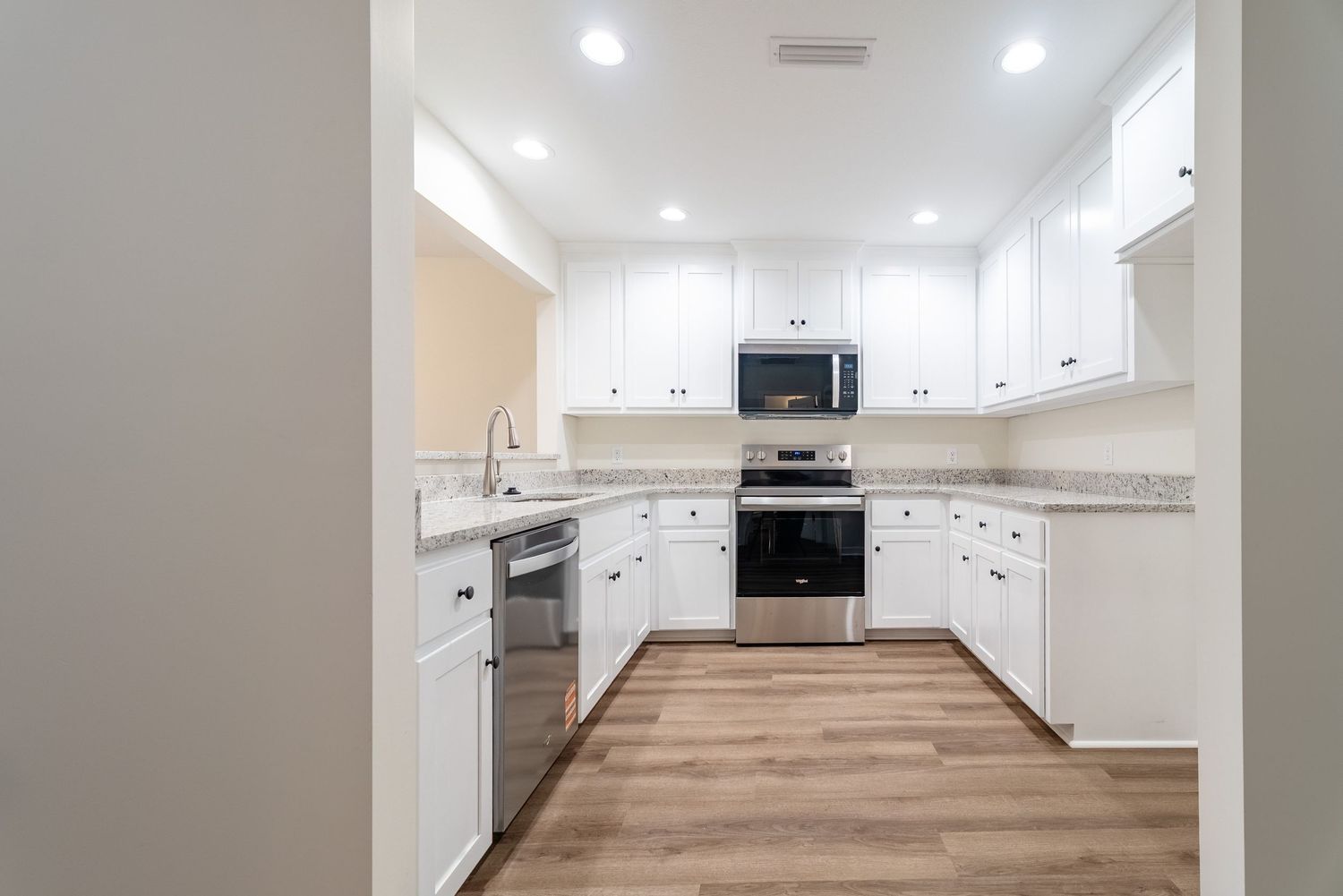 New construction kitchen with granite countertops, LVP flooring, soft close cabinetry, and stainless-steel appliances.