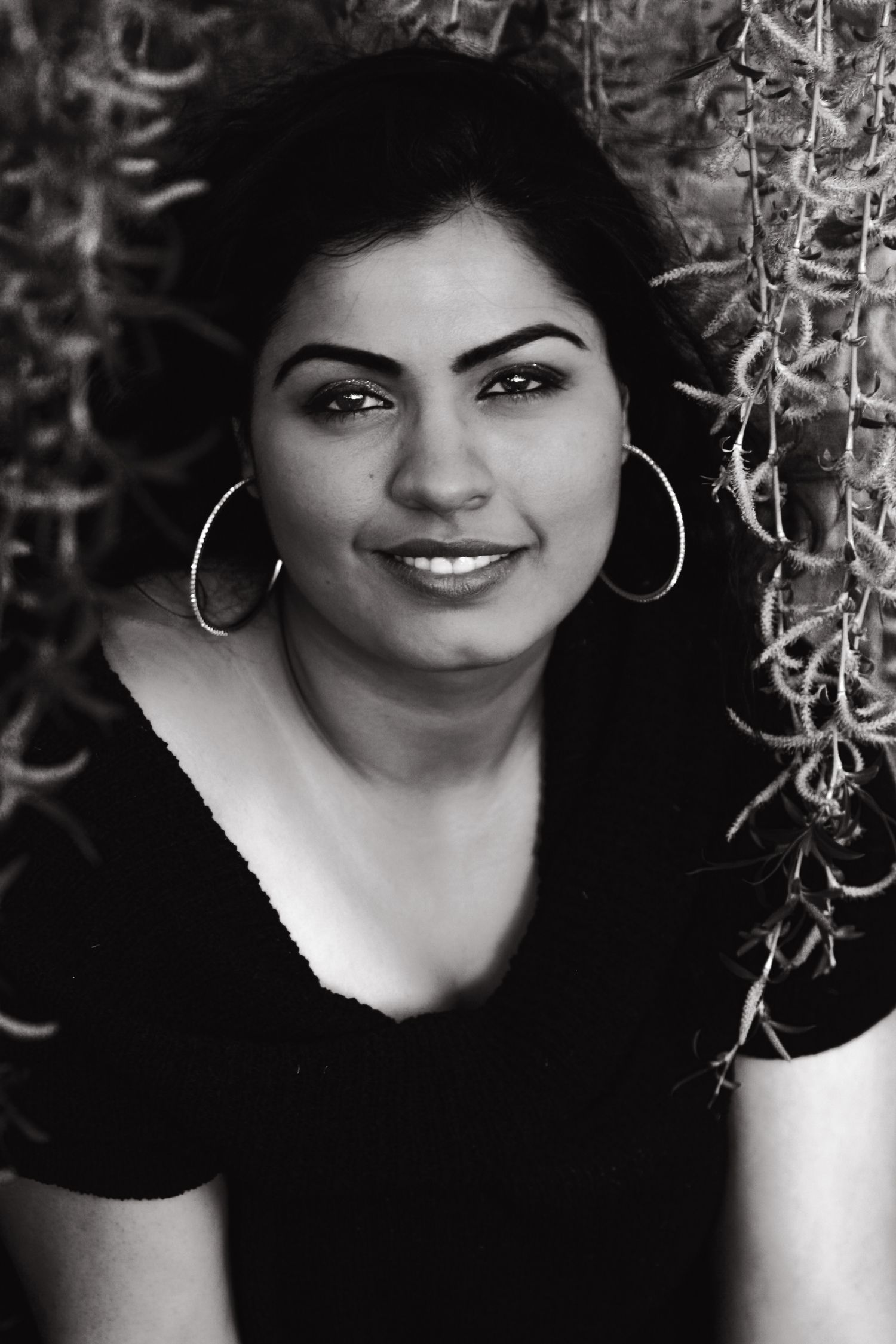 A close up photo of a young woman, in Black and White, surrounded by a willow tree.