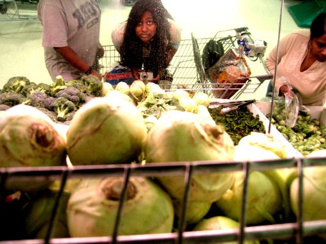 Colour photo of the photographer as a teenager looking through some produce reflected in a mirror.