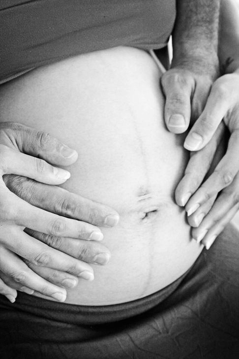 Photo of a partner and the mother-to-be in Black and White with hands on their pregnant belly.