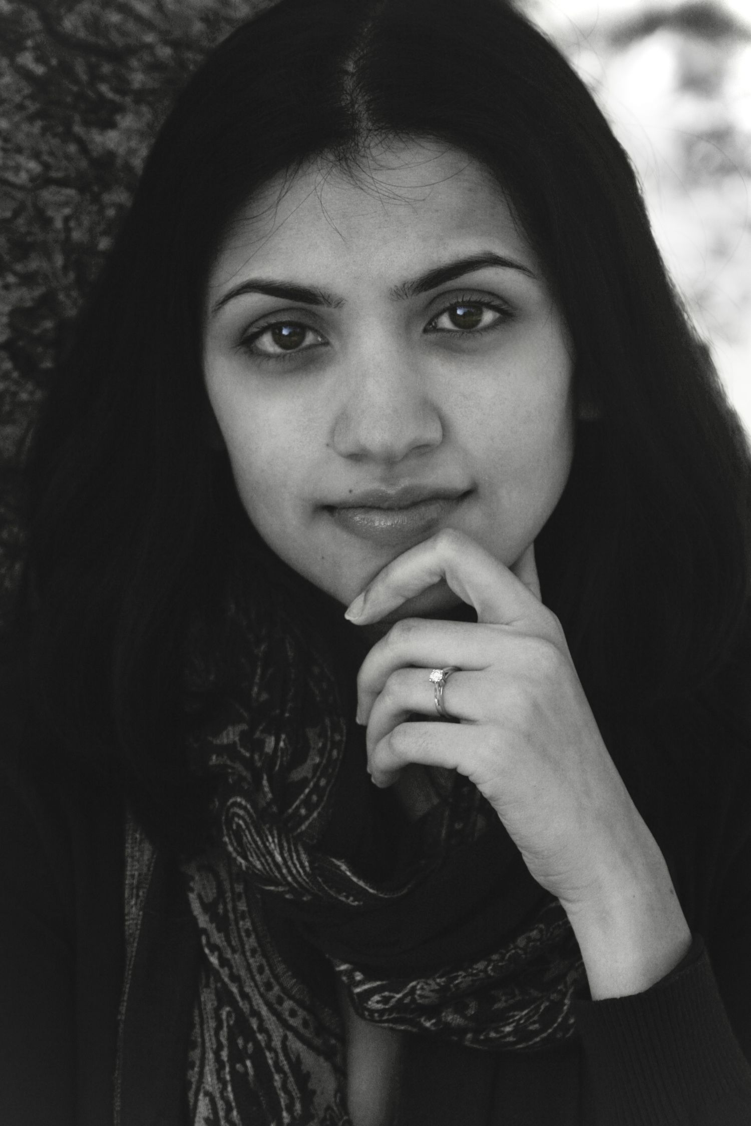 Black and White Photo of a young woman, looking directly at the camera with a somber facial expression, highlighting her engagement ring.