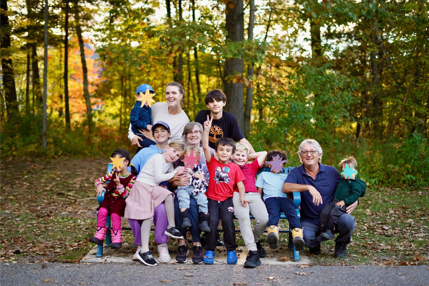 Photo of a set of grandparents with their many grandchildren, with some children's faces covered by a sticker for privacy.