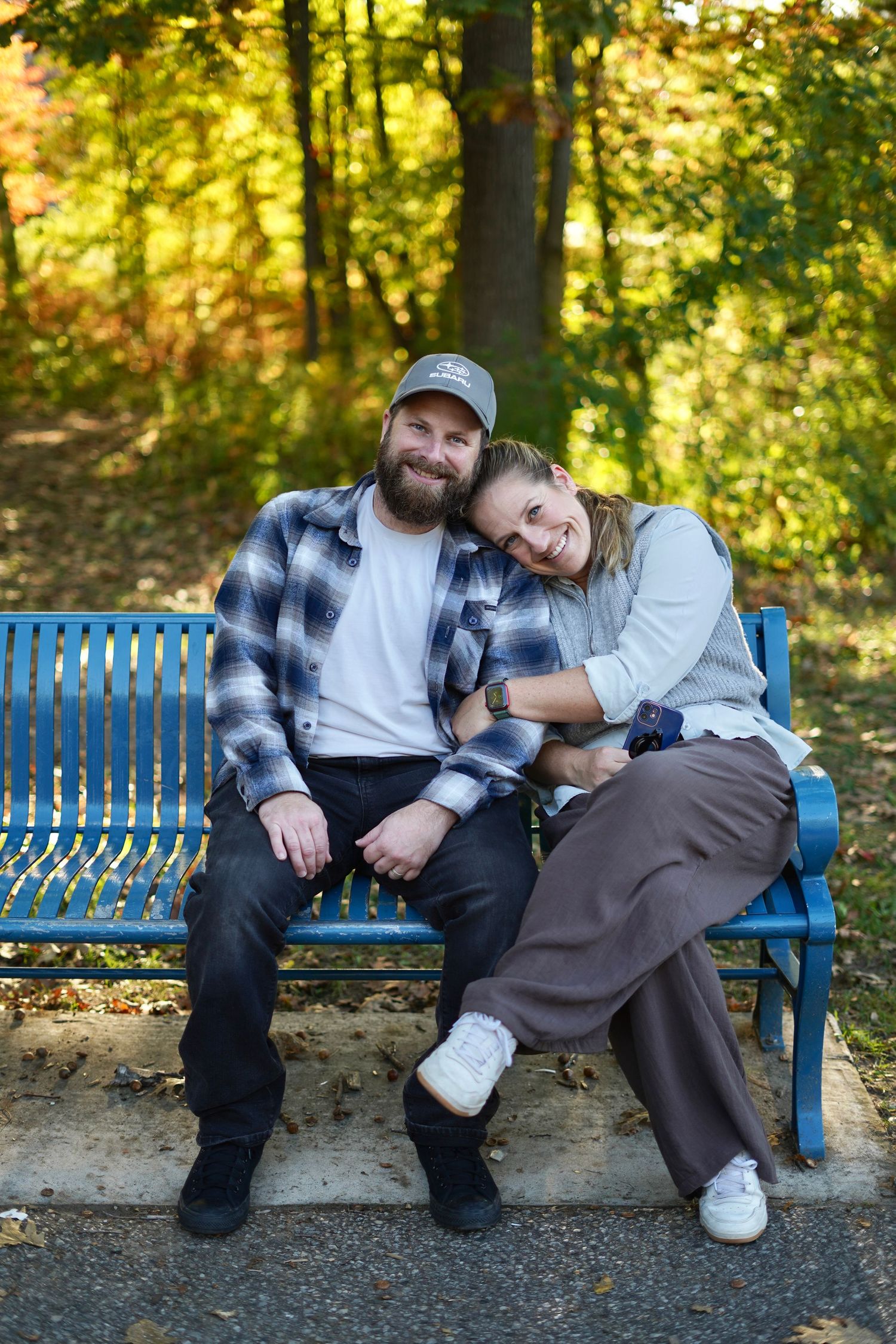 Photo of a couple, leaning into one another looking and smiling at the camera.