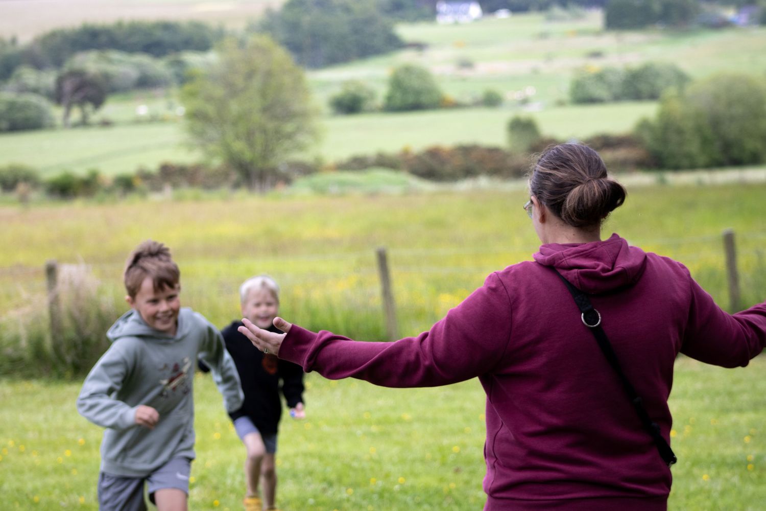 People playing and running in an open field with rolling hills in the background.