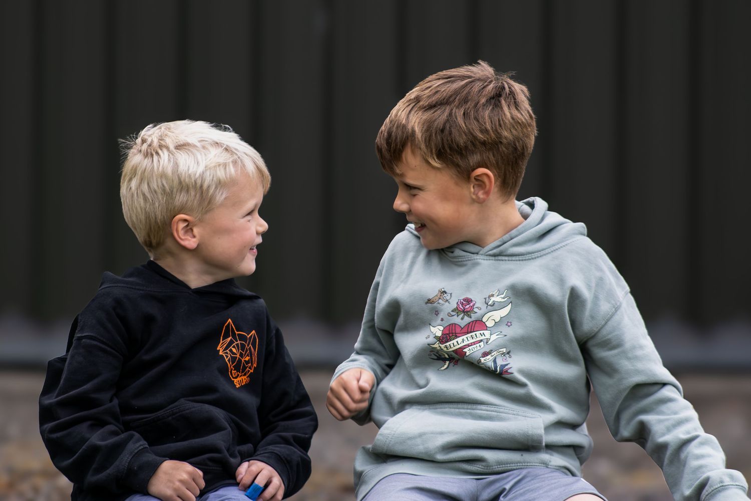 Children laughing and playing together on grass in casual clothing.
