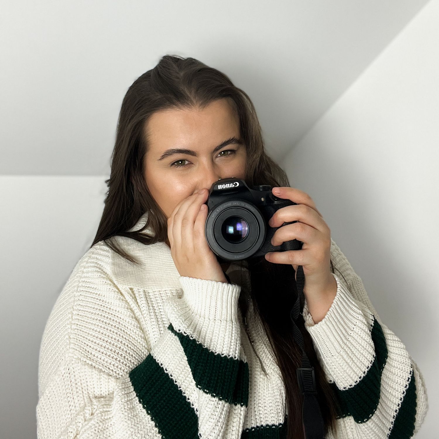 Sequence showing photographer with camera against white background wearing cozy sweater.