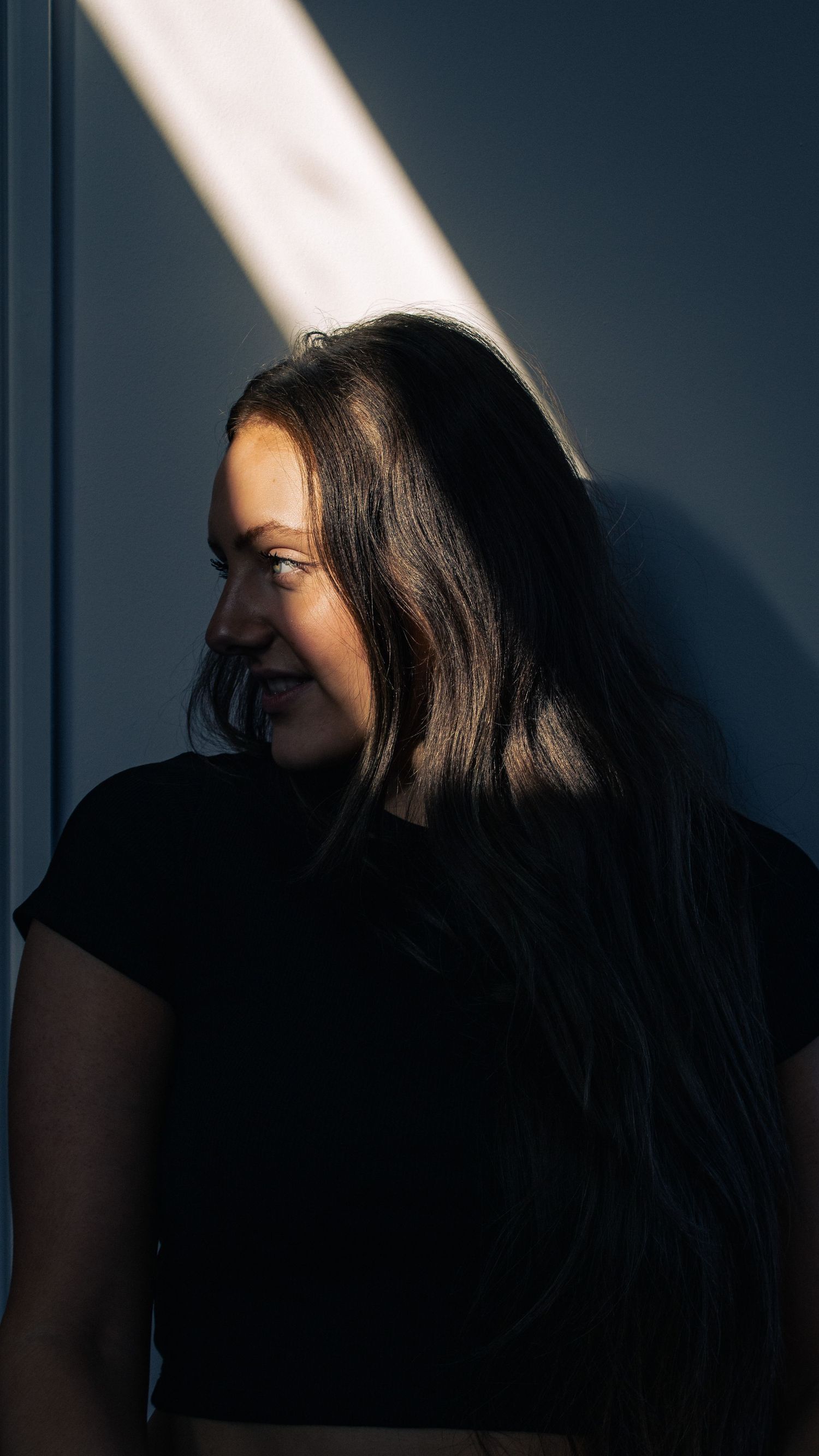Artistic portrait series with dramatic lighting and shadows against dark wall.