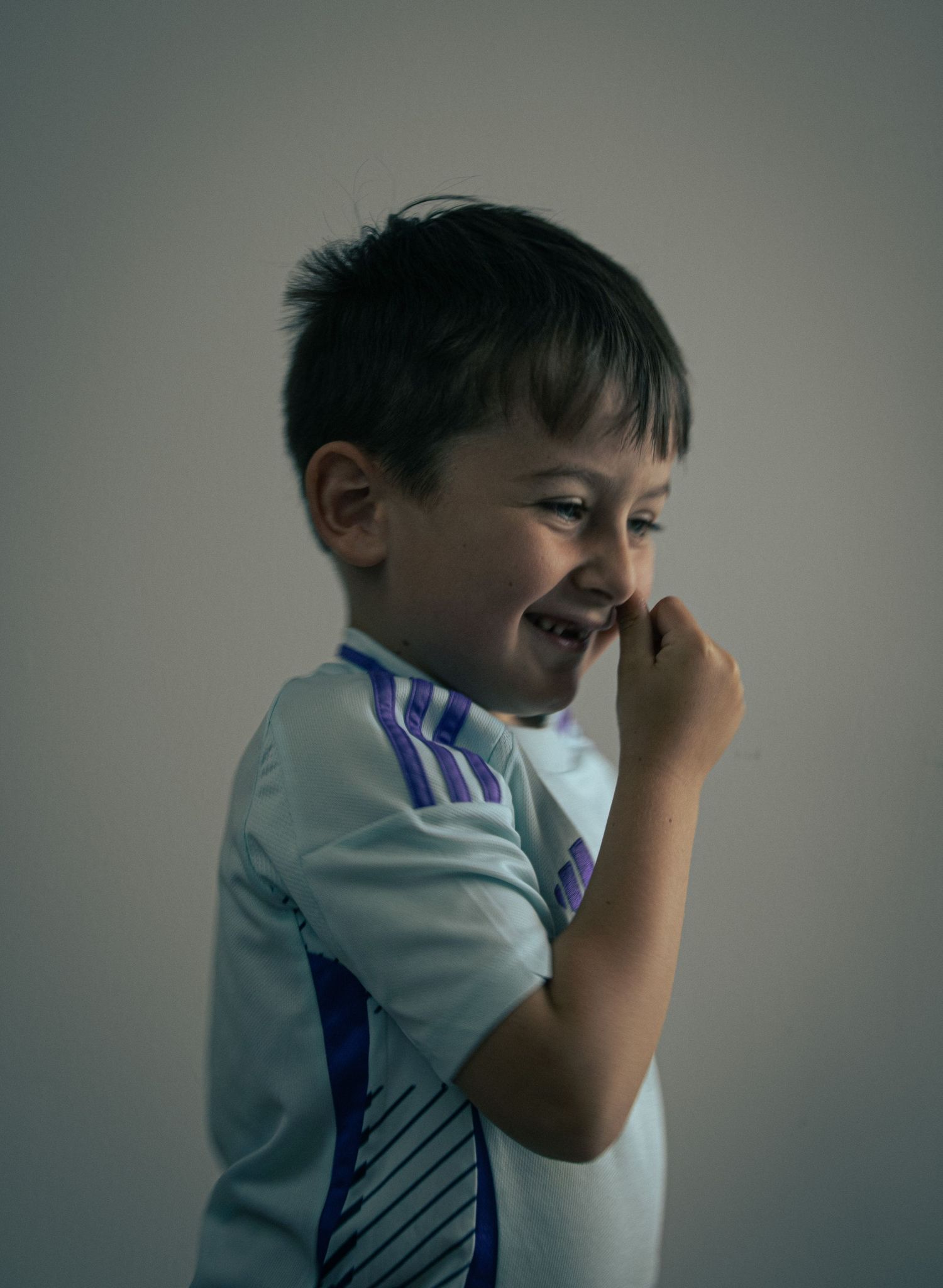 Young boy in football strip shows emotional expressions in a portrait shot.