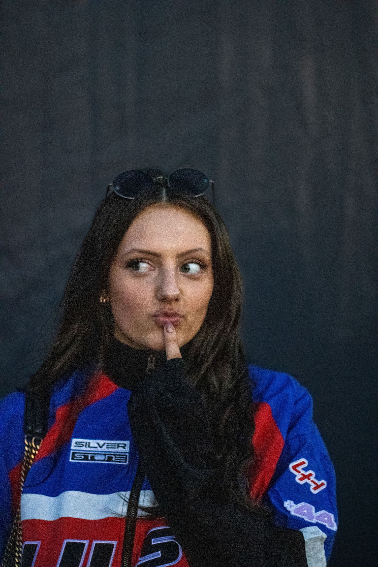 Person in red and blue sports jacket posing against dark background.