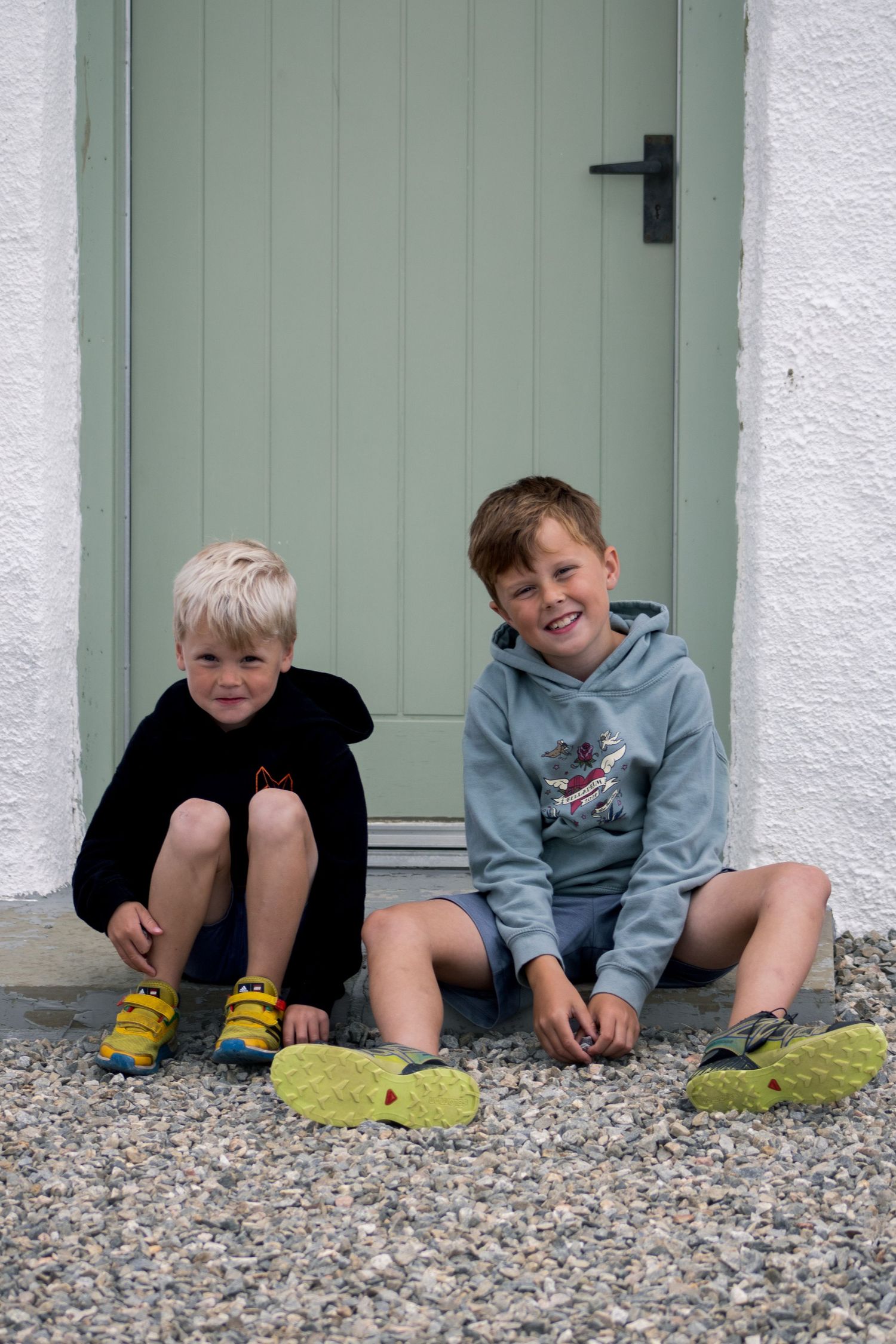 Group relaxing on gravel against white wall with mint green door in casual setting.