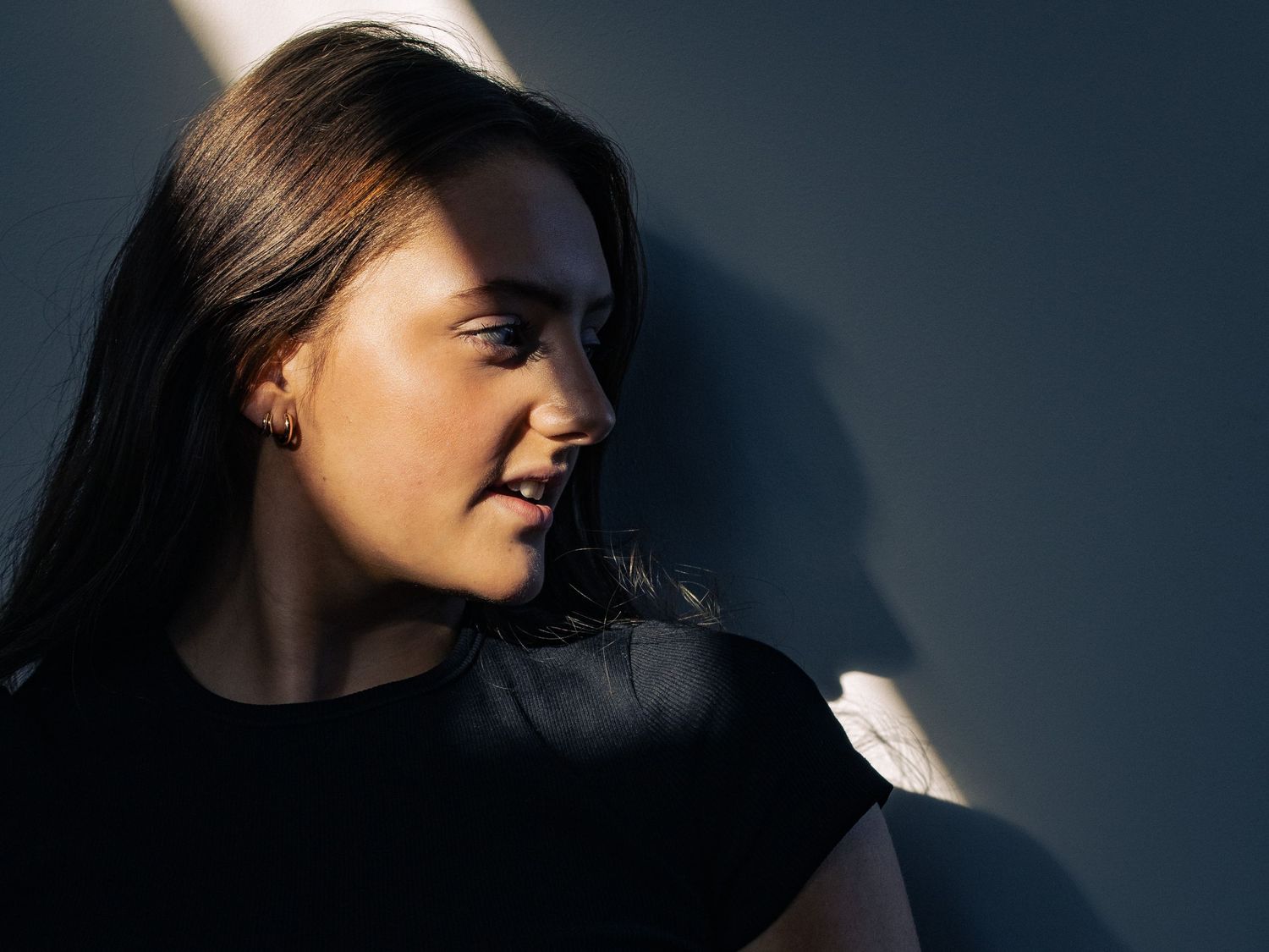Dramatic side-lit portrait series with strong shadow contrast.