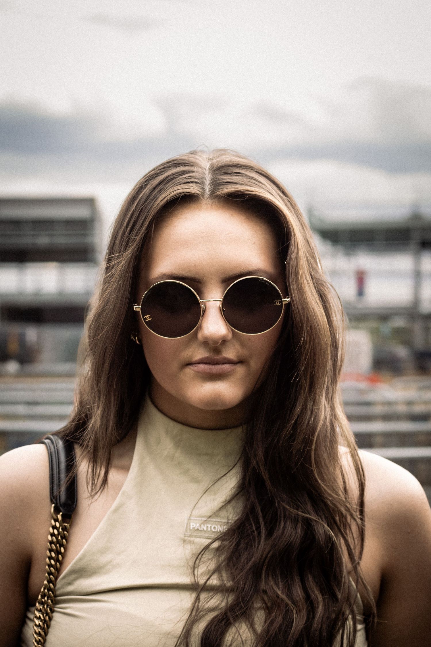 Portrait series of person in sunglasses and cream top against urban backdrop.