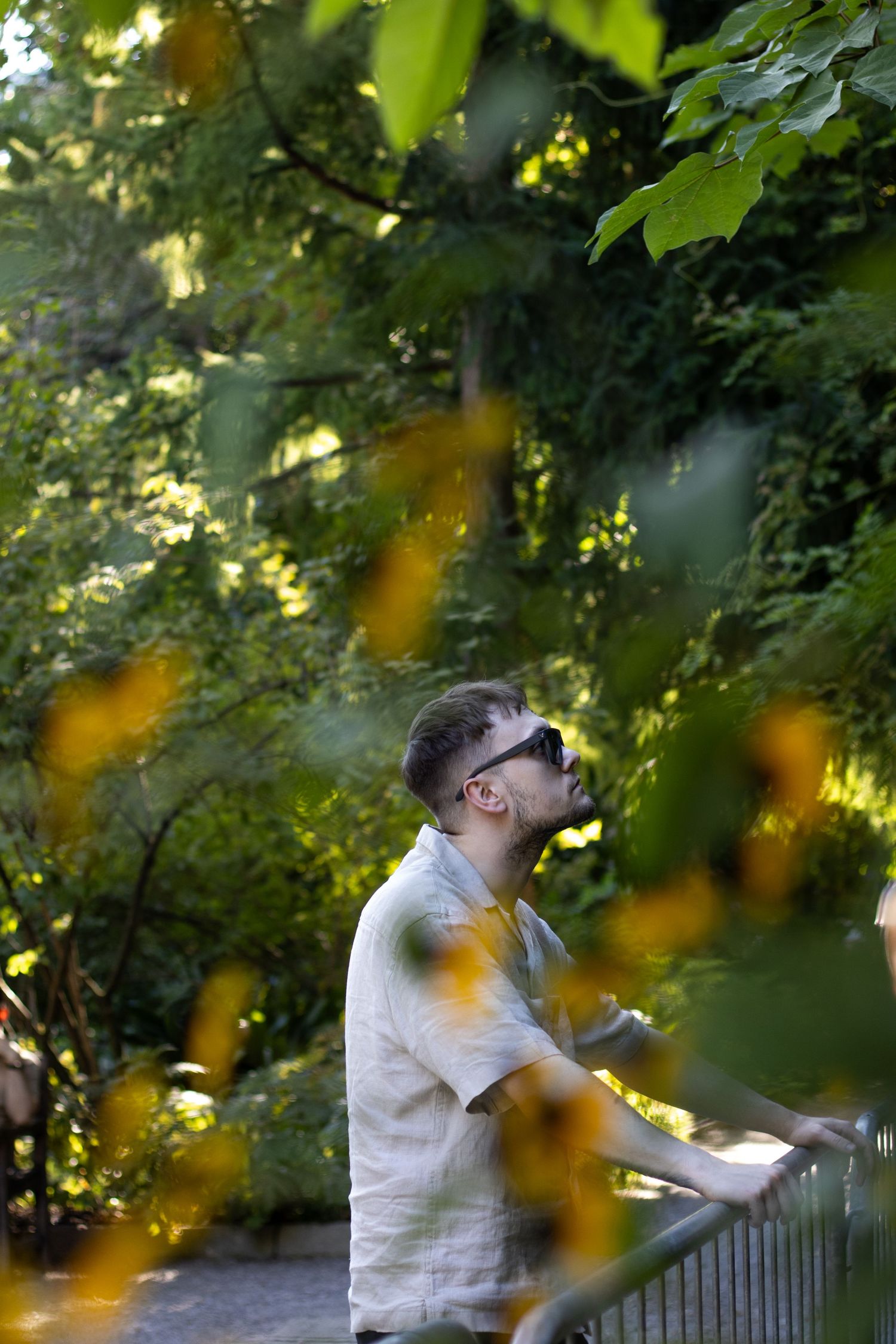 Person in white shirt viewed through leaves enjoying outdoor scenery.
