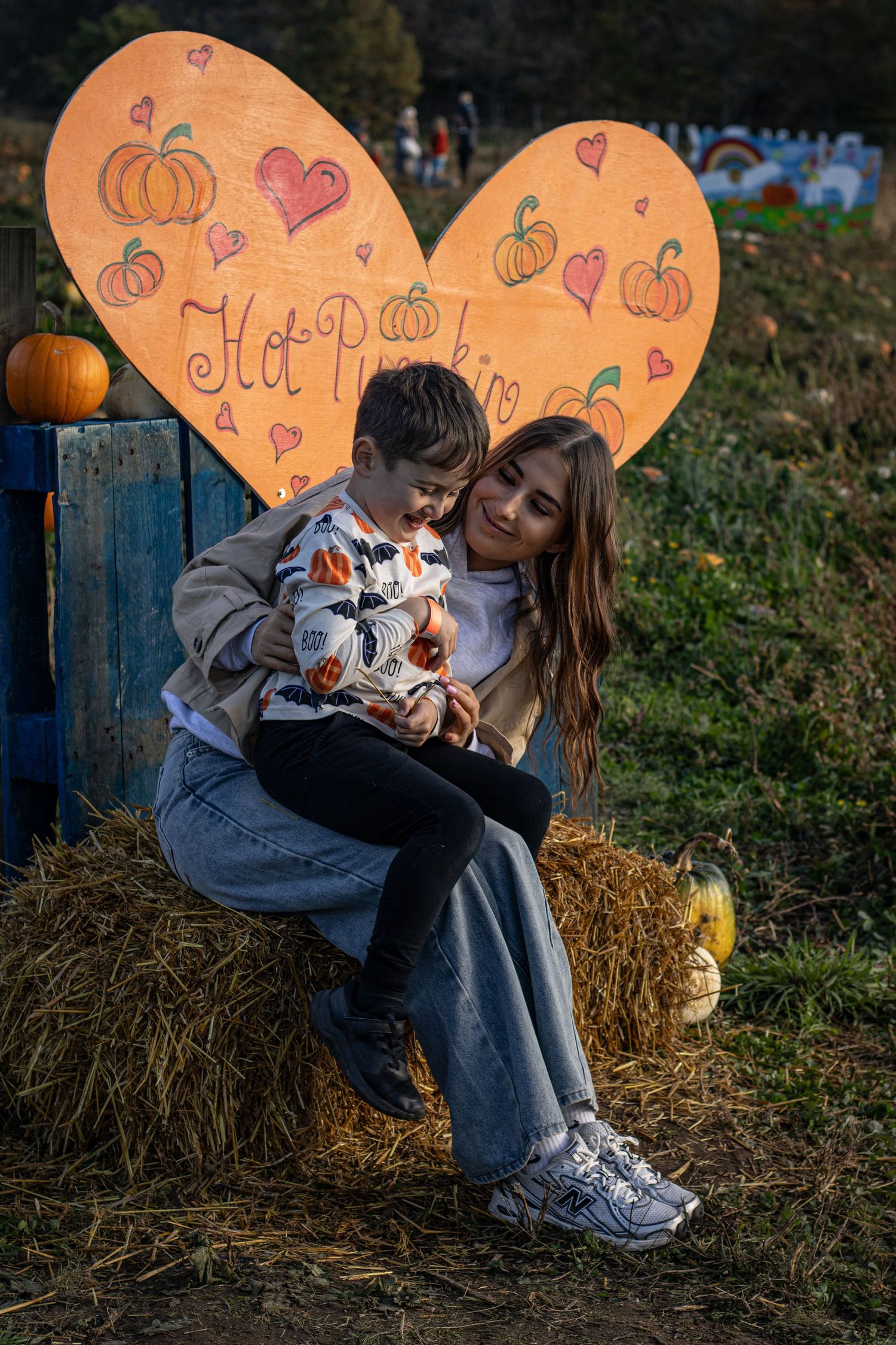 Autumn scene with pumpkin decorations and heart artwork on hay bales at dusk.