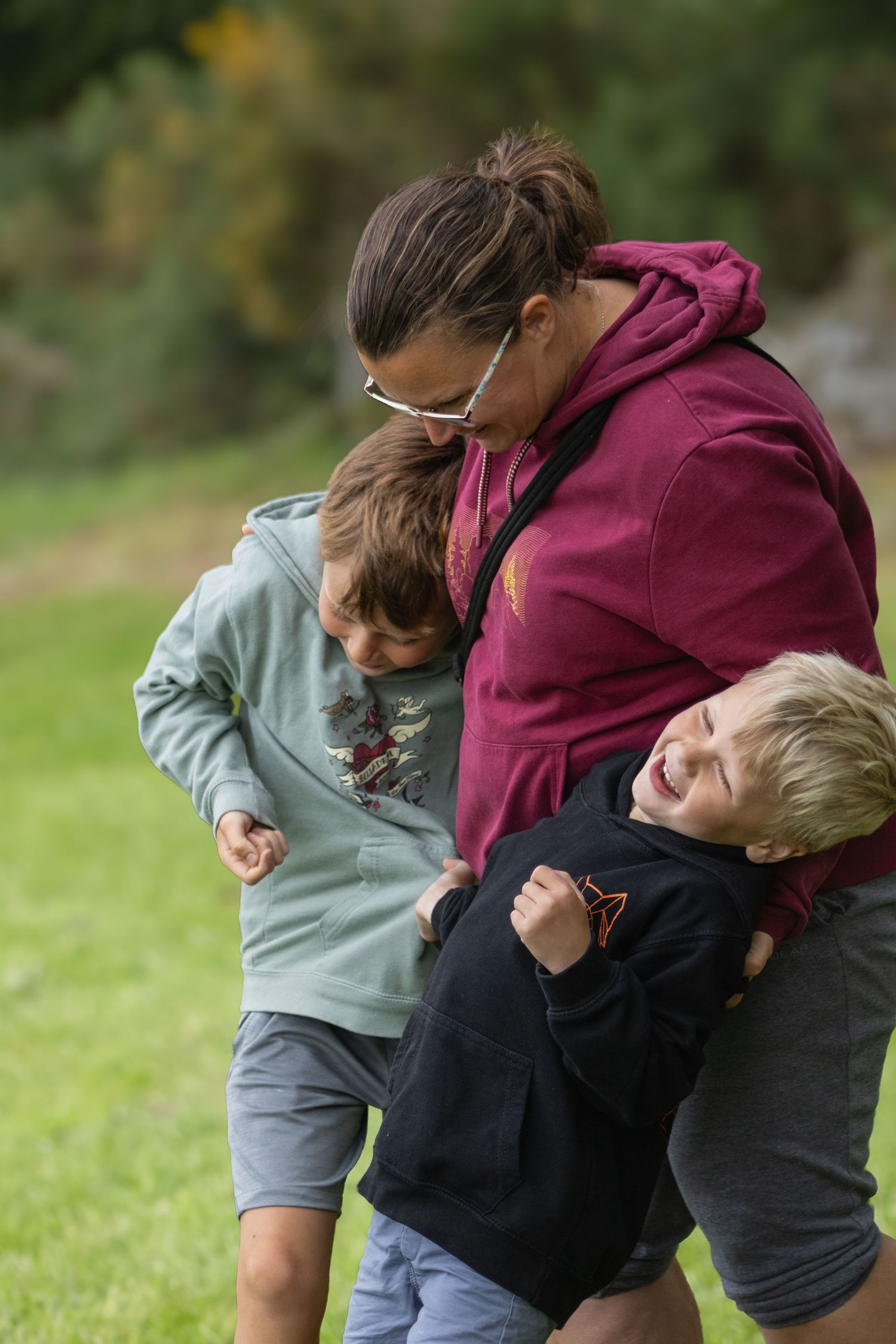Playful family moment captured outdoors with adults and children in casual clothing.