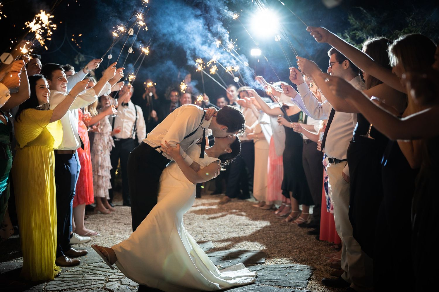 Dramatic nighttime sparkler exit with wedding guests lining the pathway.