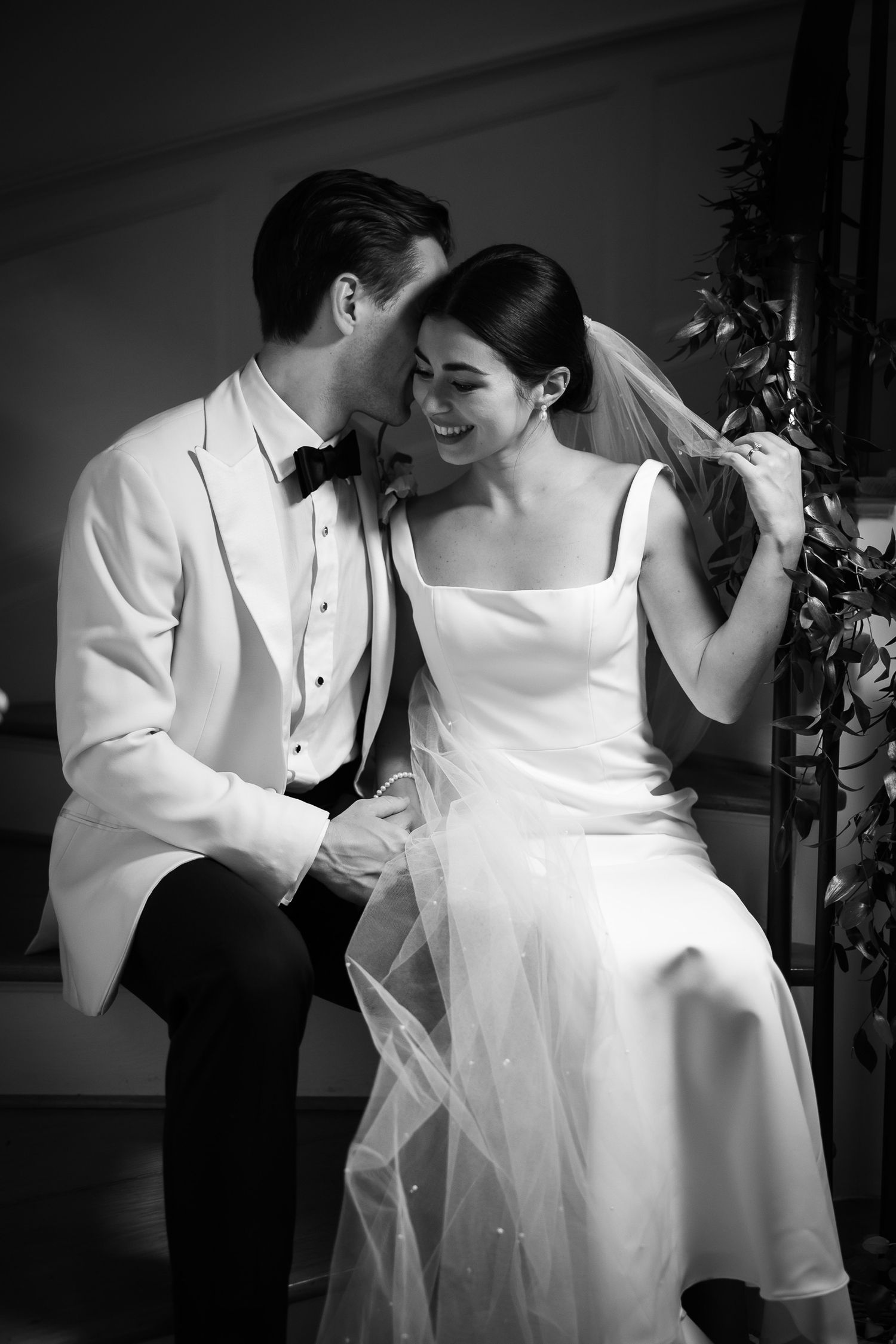 A black and white portrait of a tender wedding moment between the couple.