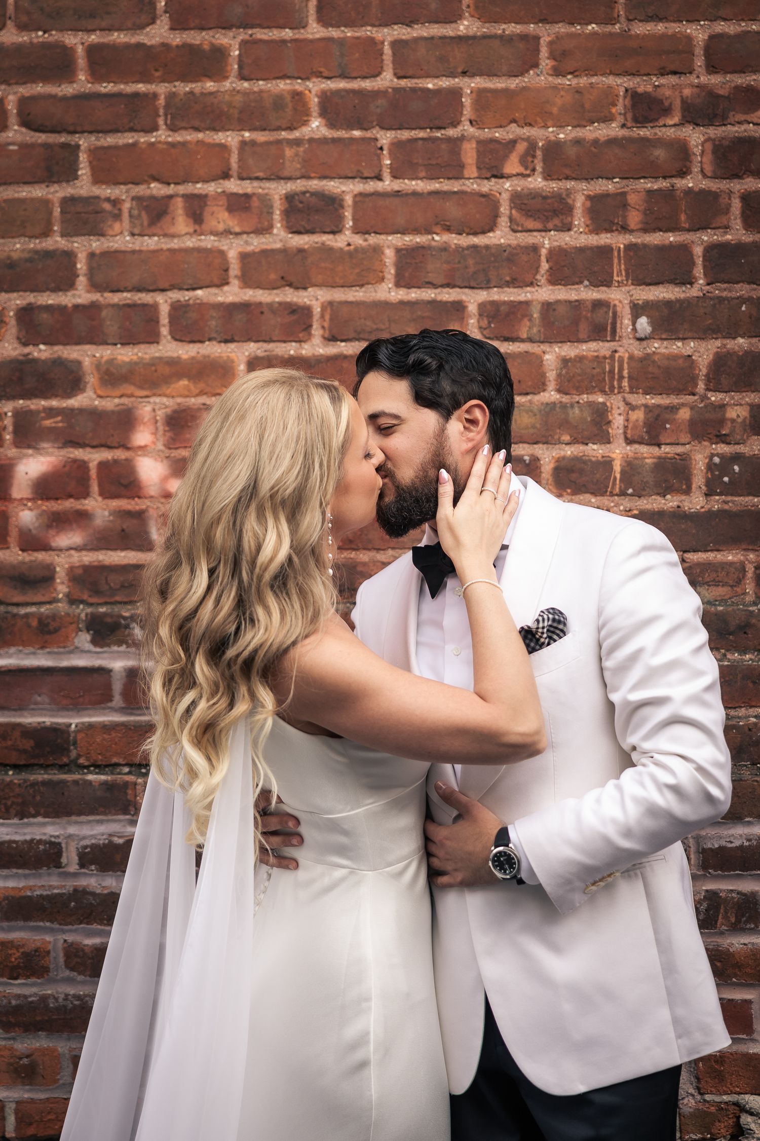 A romantic series of wedding photos showing a couple sharing a kiss against a rustic brick wall background.