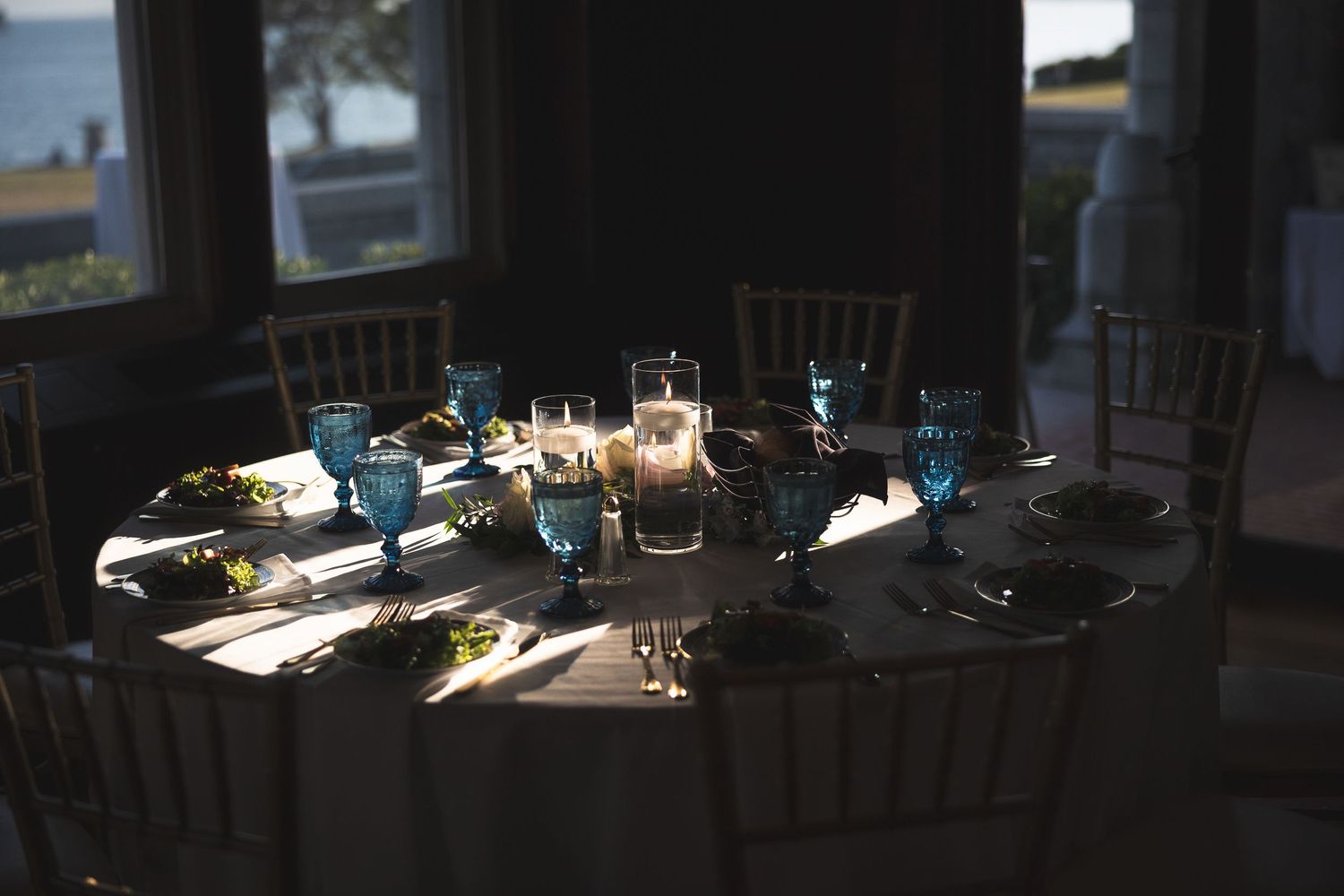 Sunlight streams through windows into a dark room casting dramatic shadows on dining tables and chairs.