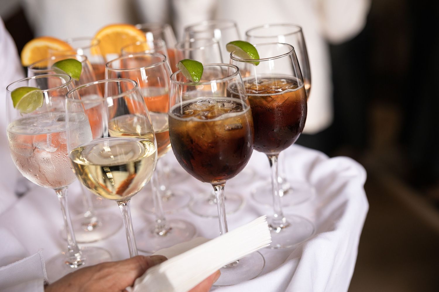 Various wine glasses and cocktails arranged on a white cloth at an event.