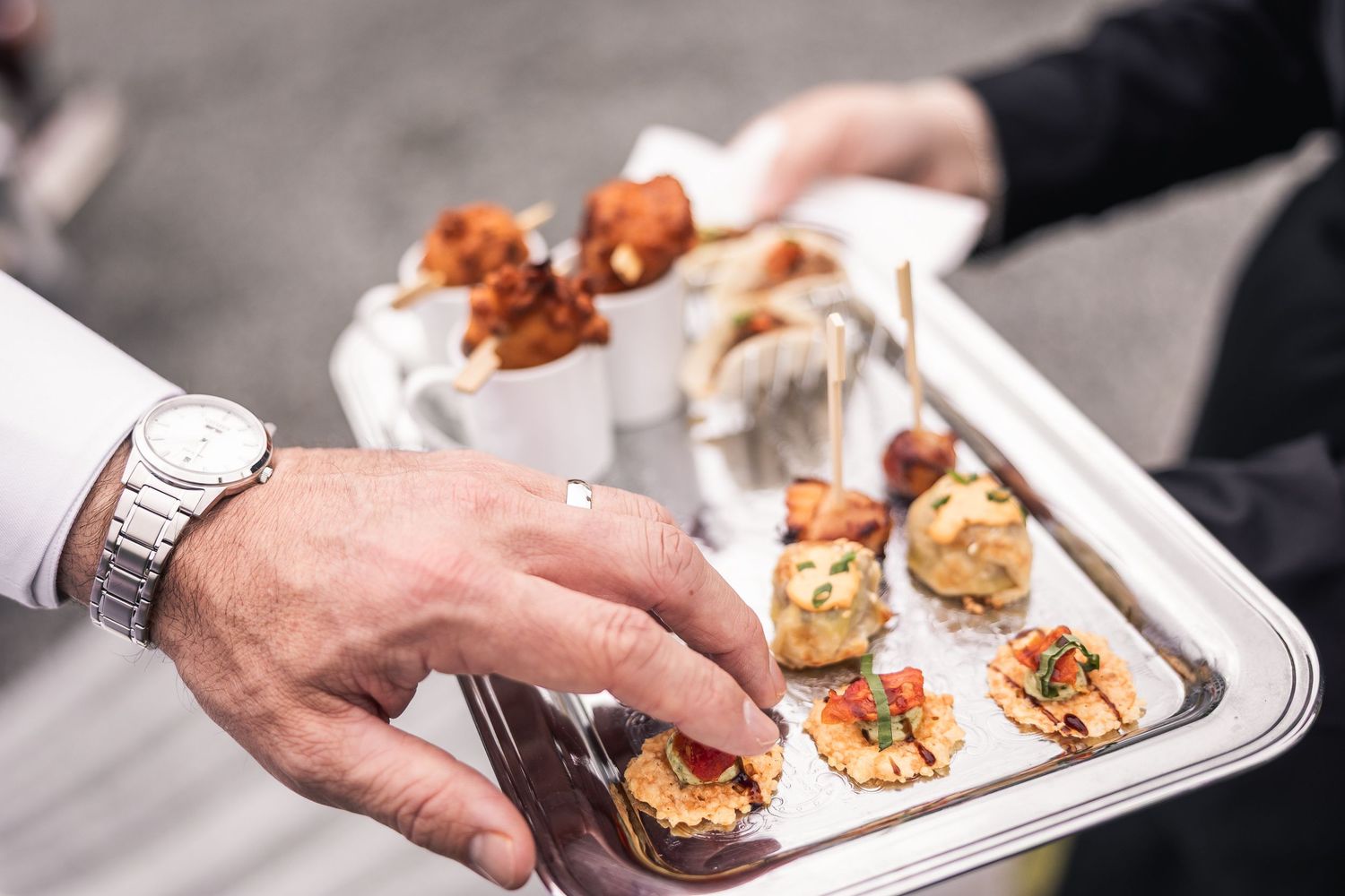 Catering staff serves appetizers on white plates at an elegant event.
