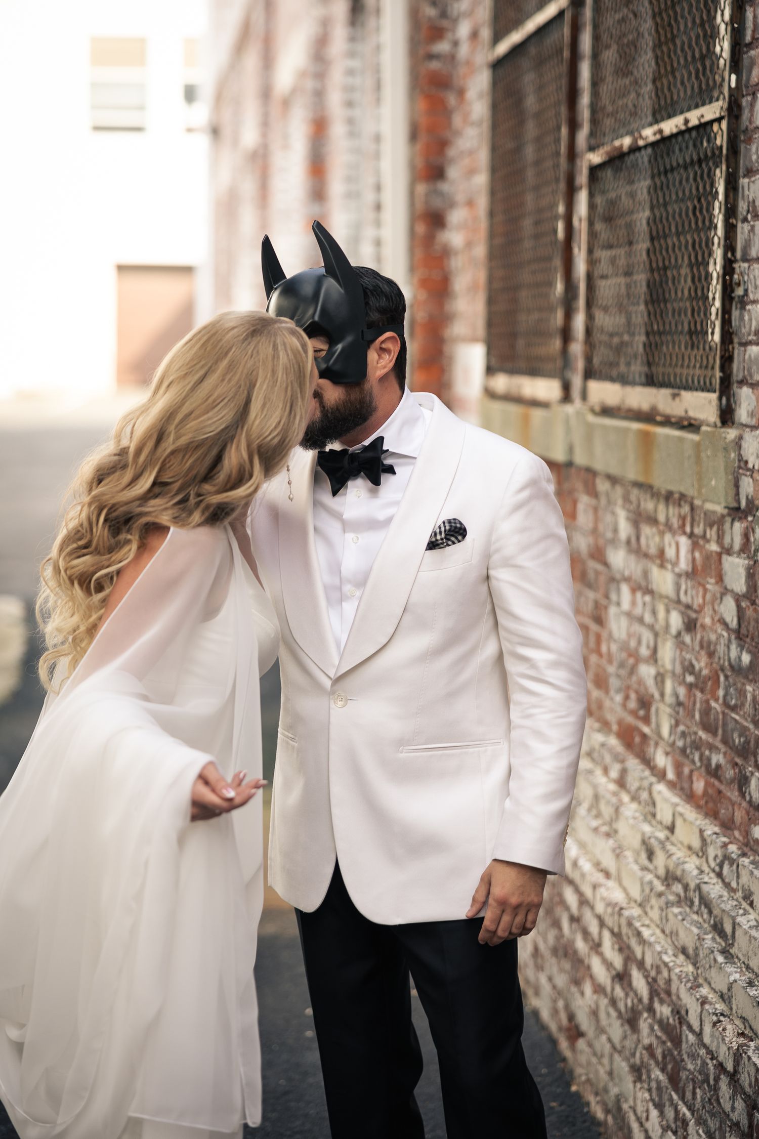 Romantic couple in formal attire sharing intimate moments against a rustic brick wall in a series of artistic photos.